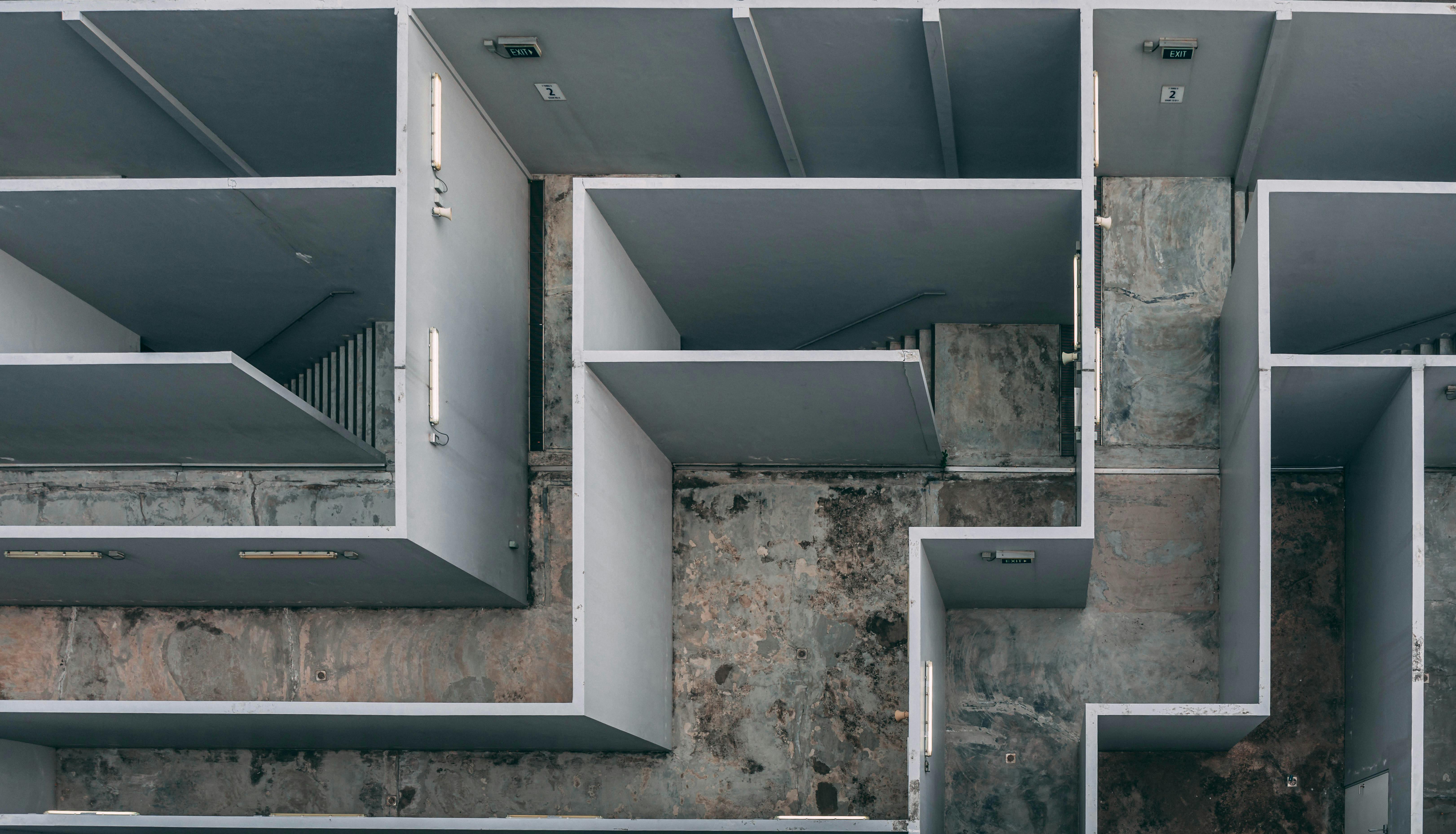 Aerial view of an unfinished building interior with gray partition walls and exposed concrete floors