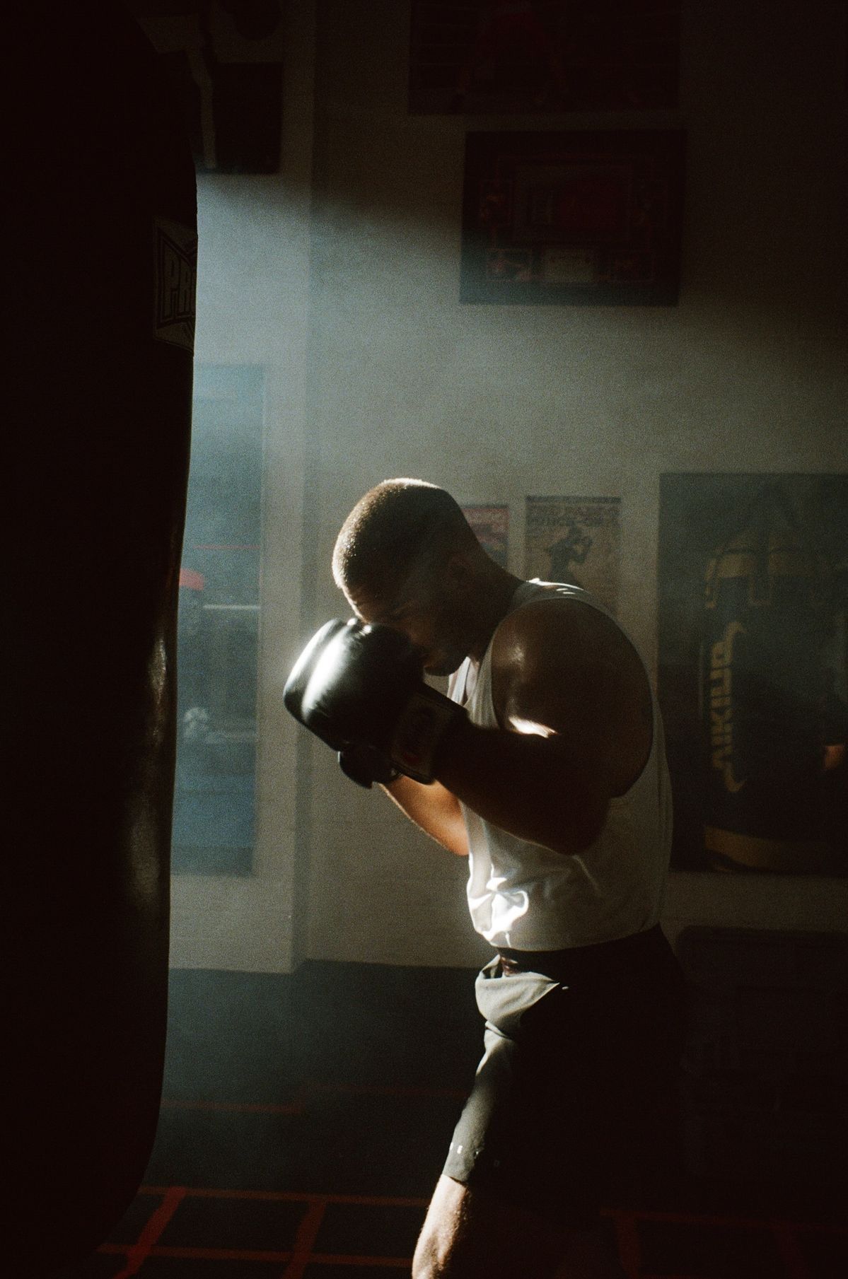 Boxer hitting a heavy bag in a dramatic spotlight.
