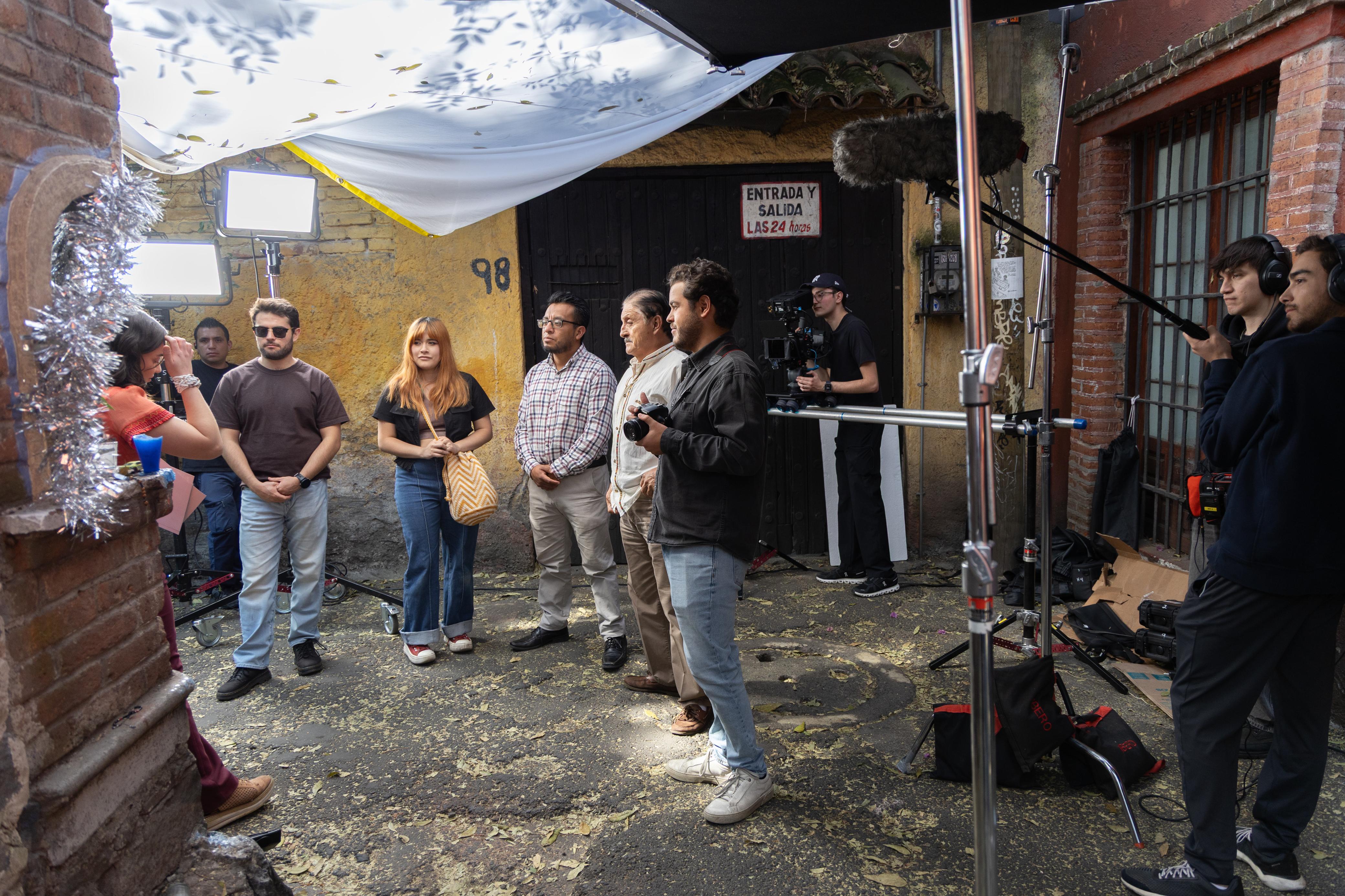 Production crew and talent working in a secure, scouted courtyard location in Mexico City managed by Mauricio Nader. The scene demonstrates logistical efficiency, local fixing intelligence, and safety protocols for on-location filming.