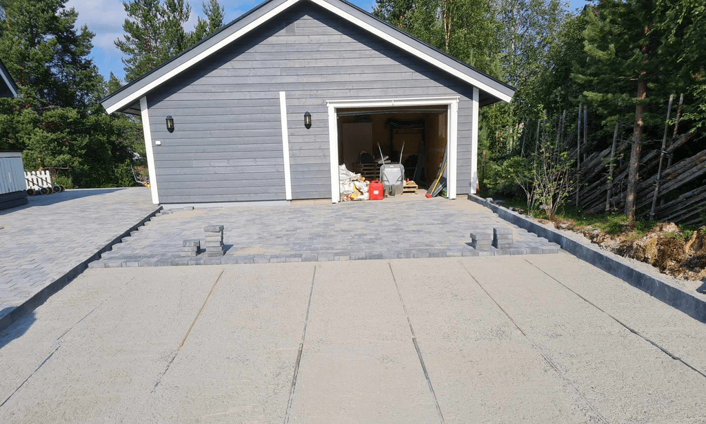 Garasje med steinlagt parkeringsplass.