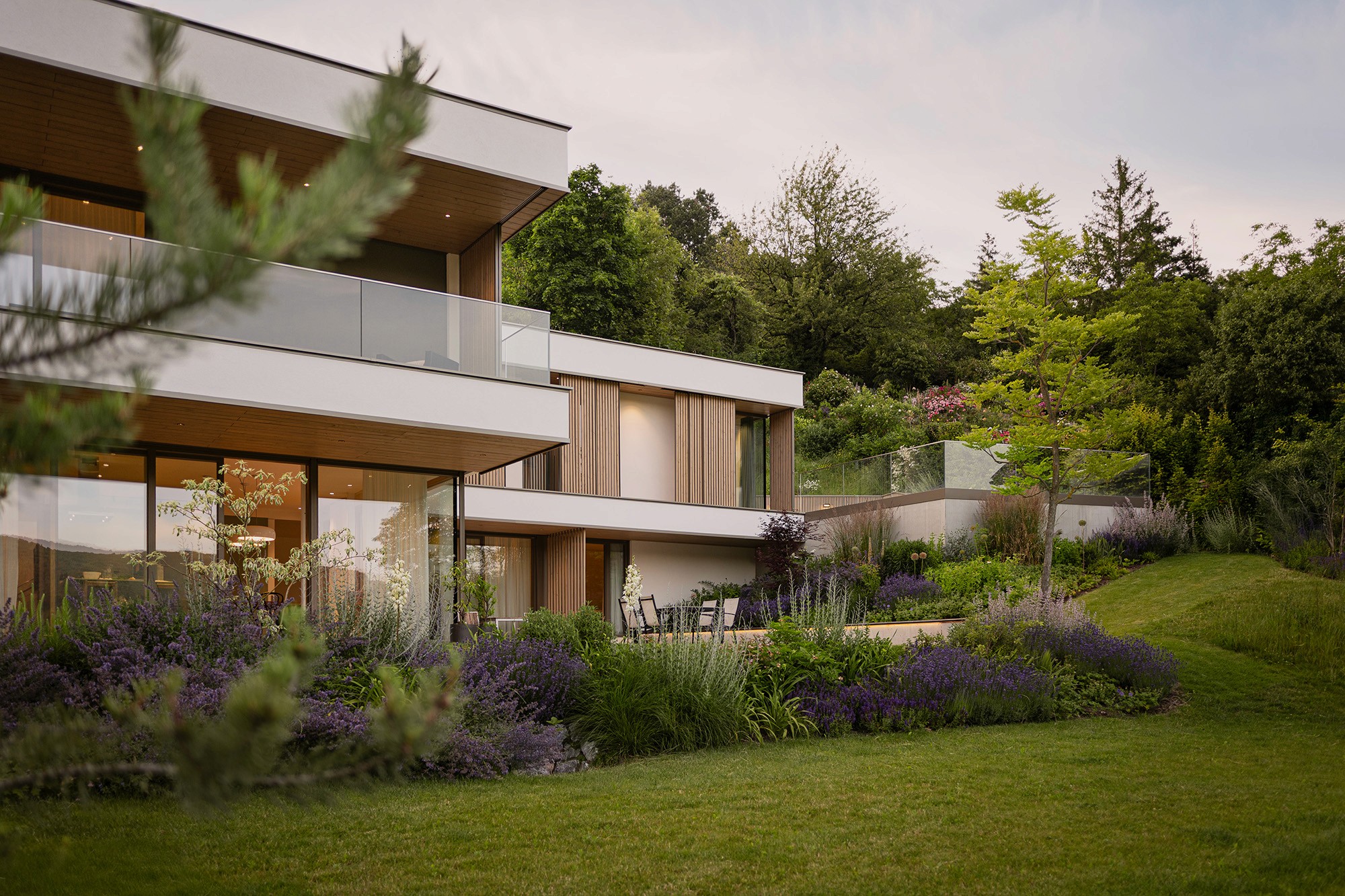 Großzügiger Garten mit Rasenfläche, Staudenbeeten und moderner Architektur.