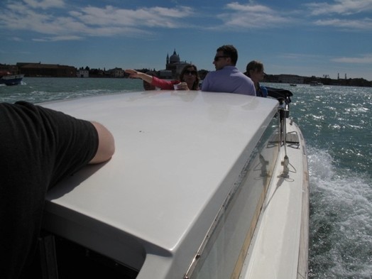 A photo of a group of people sitting on a boat near the coast.