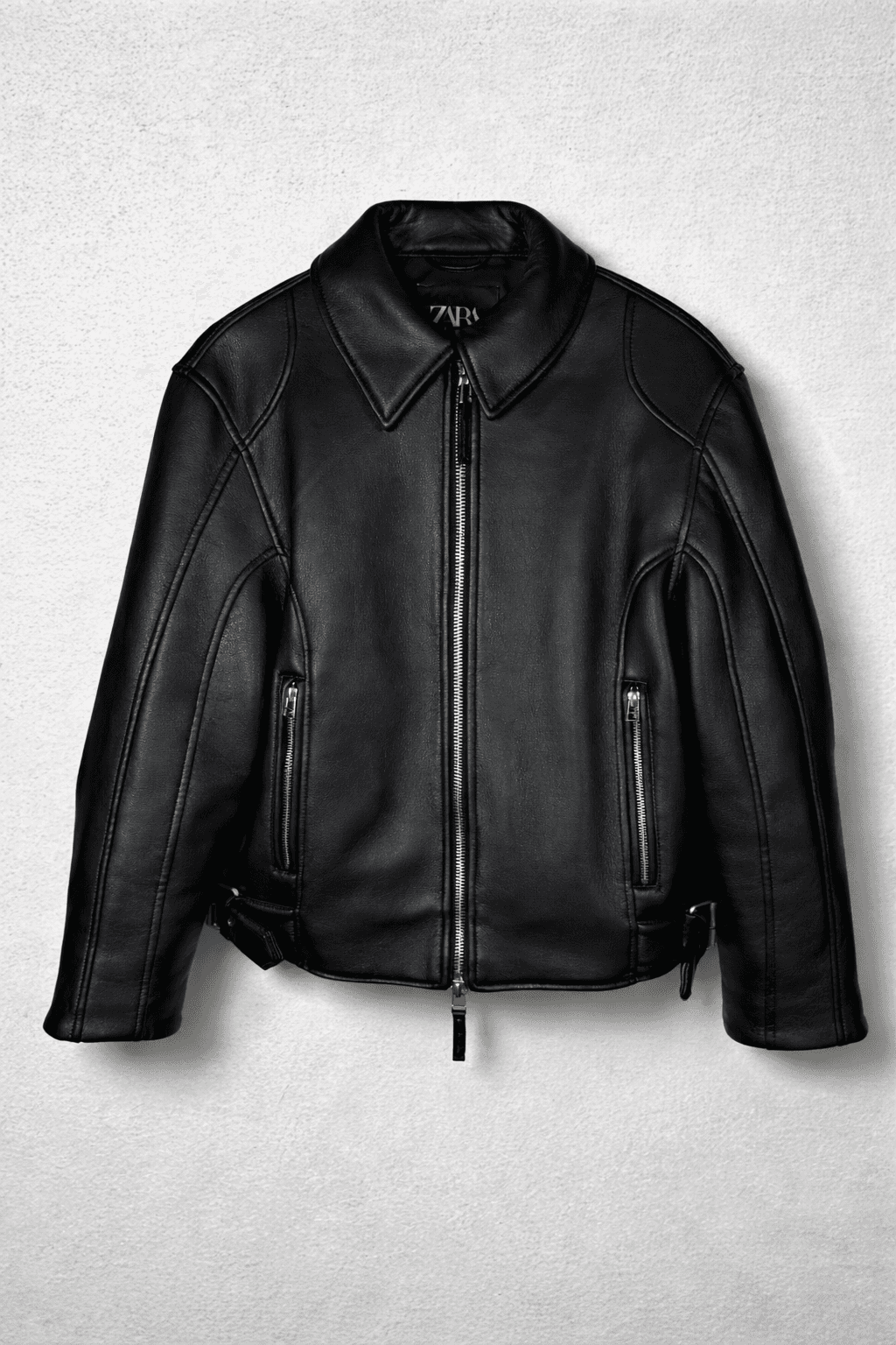 Black leather jacket with collar and zippered pockets.