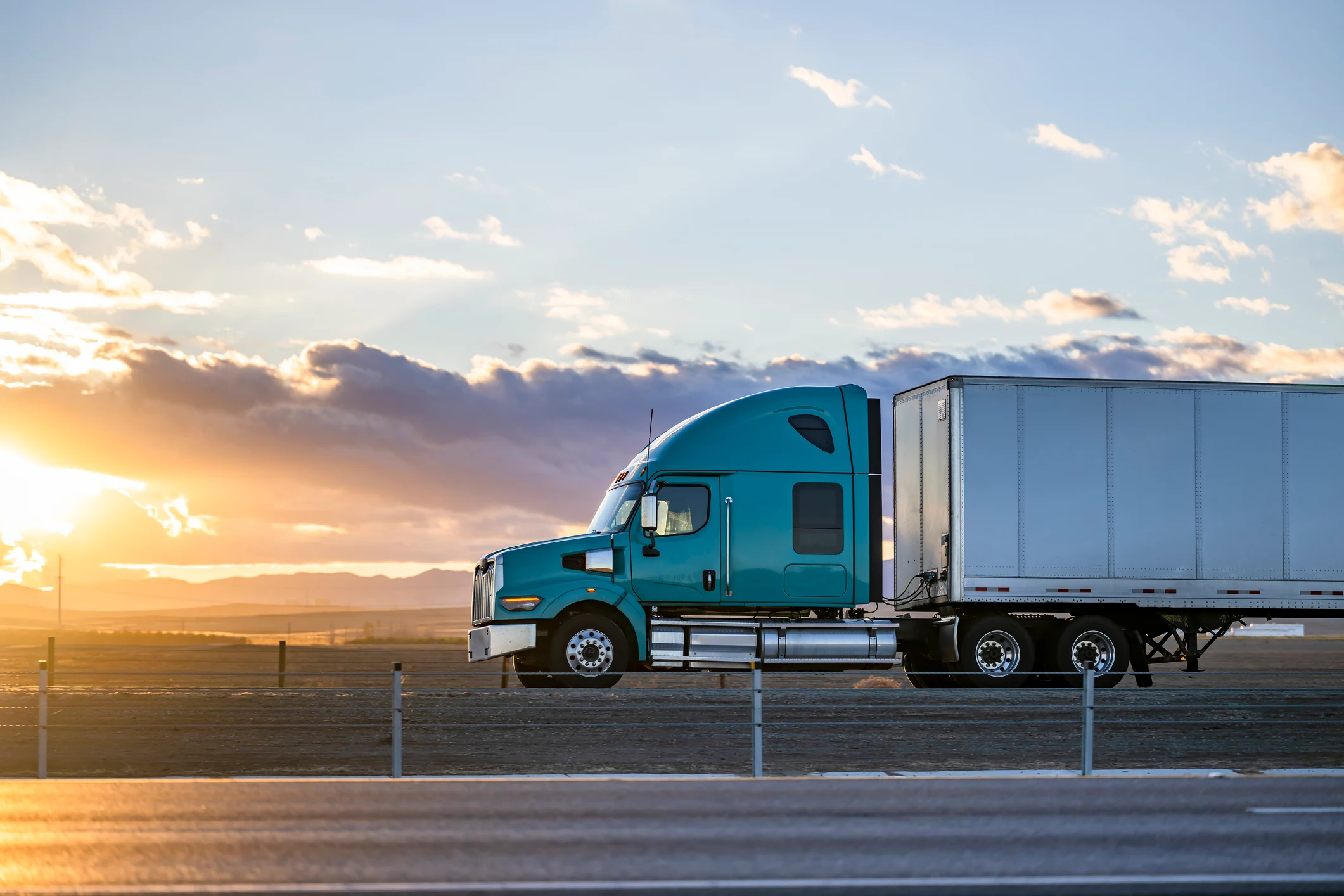 Blue semi-truck with a box trailer parked at sunset on an open highway — used on the GIA Group, LLC Success Stories page to represent growth and achievement in the trucking industry