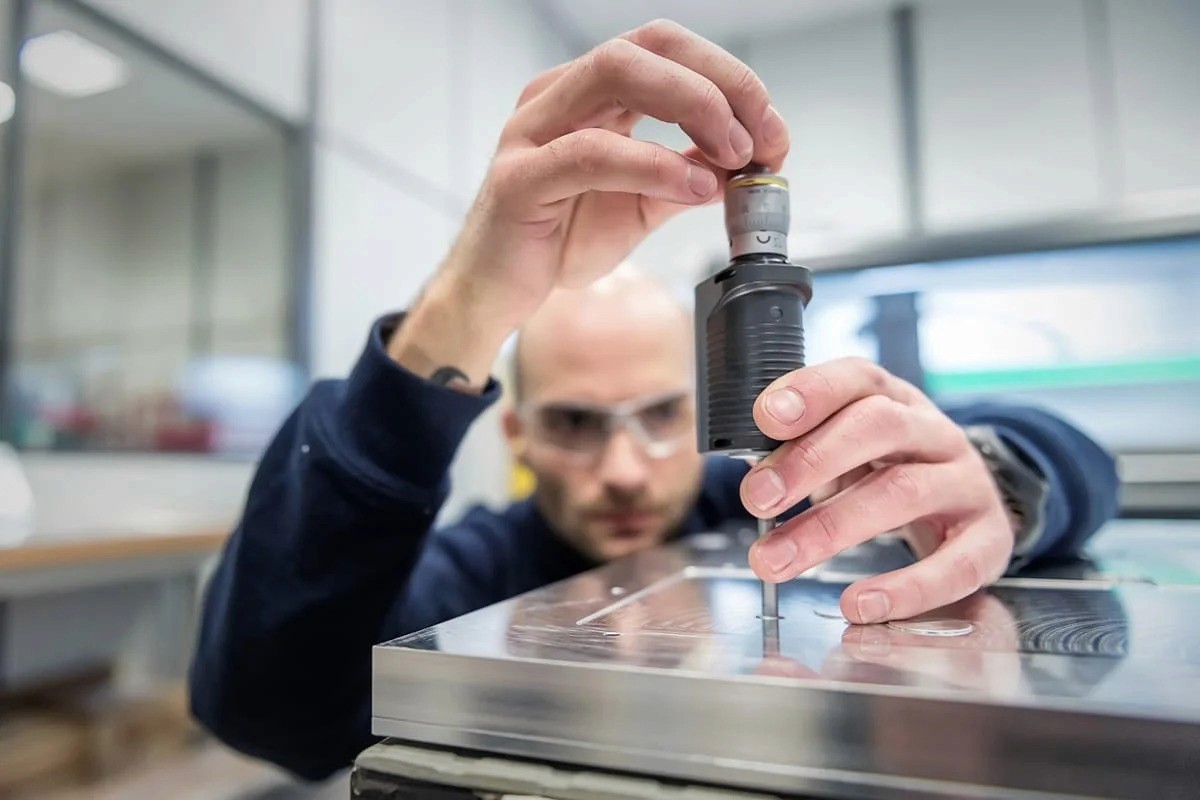 Technicien ajustant pièce mécanique de précision — photographie corporate Lille Nord | Anteale Yann Manac’h 2025