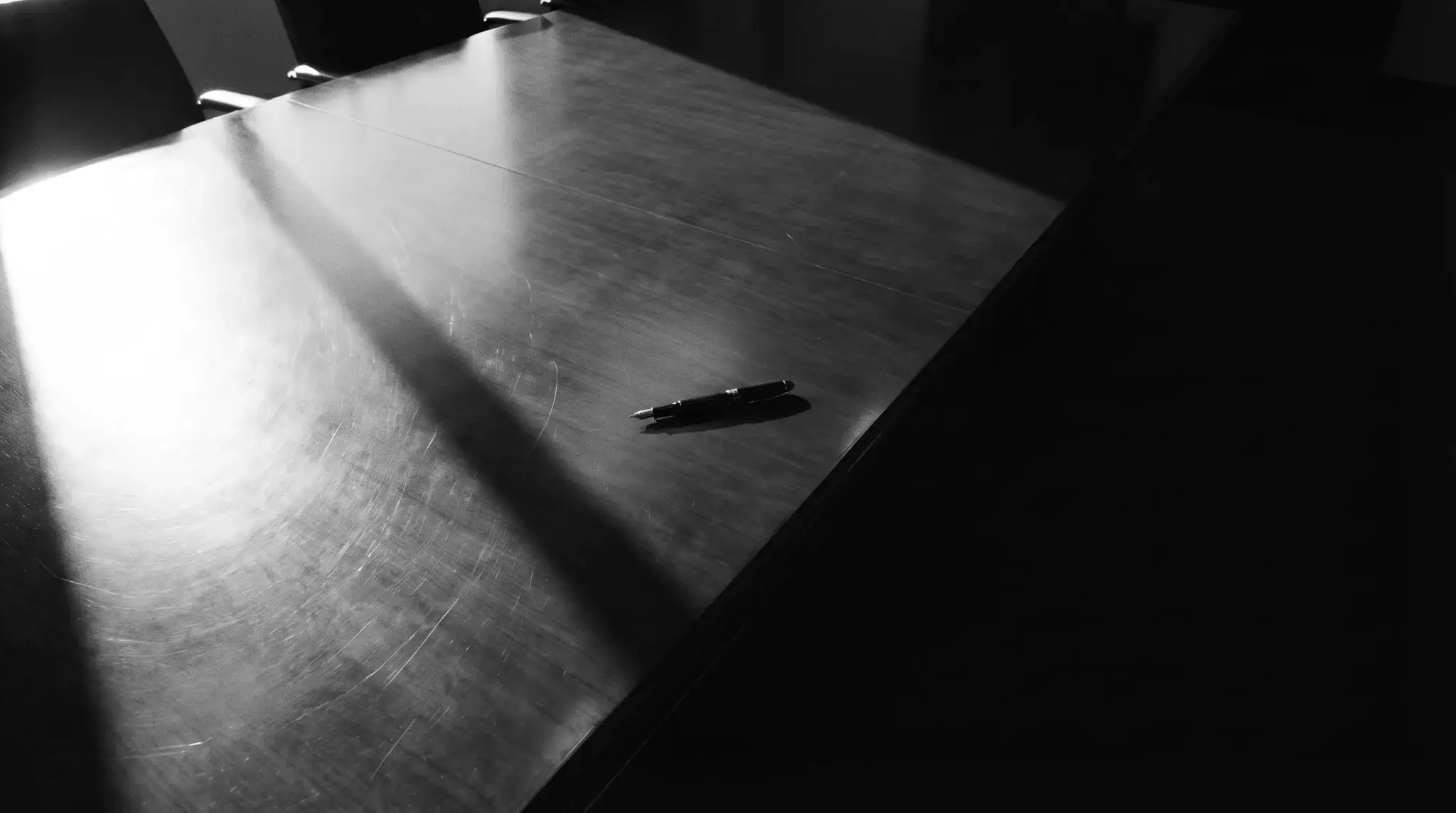 Photographie noir et blanc d'une table de réunion et d'un stylo plume, illustrant l'accompagnement en droit des sociétés à Paris par STC Avocat.