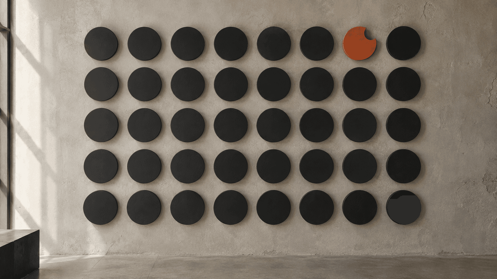 Precise grid of black circles interrupted by one notched orange ceramic element