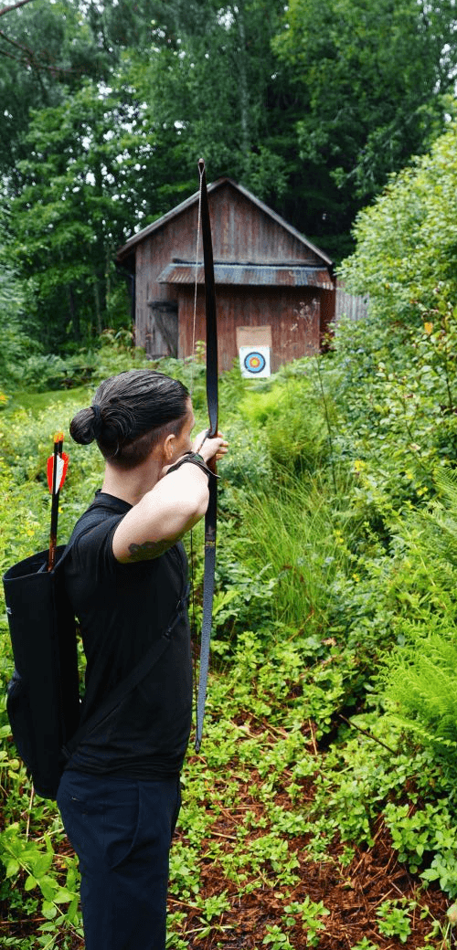 Person practicing archery in a forest, aiming toward a distant target — symbolizing focus and clarity.