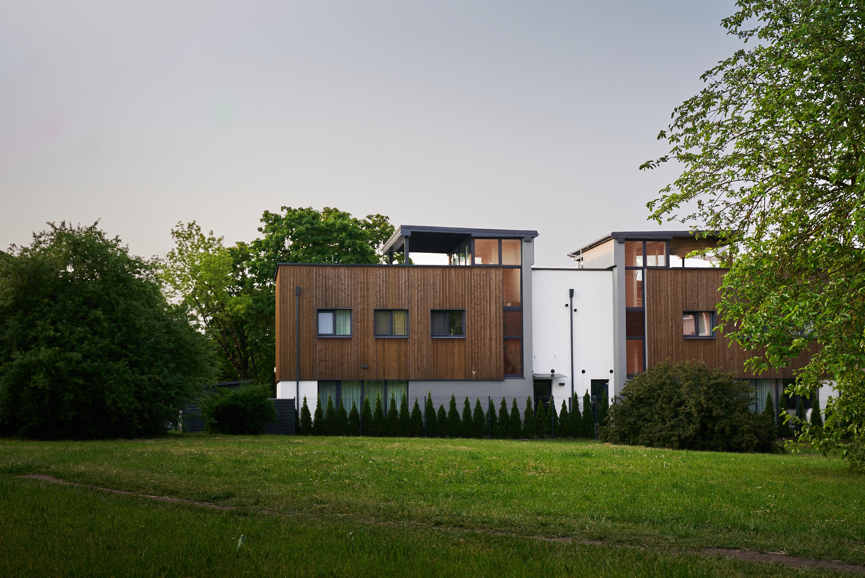 Modern brick building surrounded by greenery, featuring large windows and a flat roof in a serene setting.