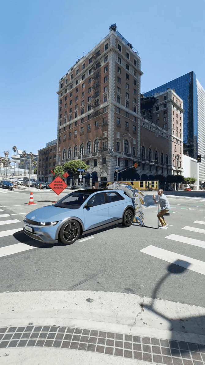 A sleek blue Hyundai driving through a city intersection with a digital "Mixed Reality" overlay.