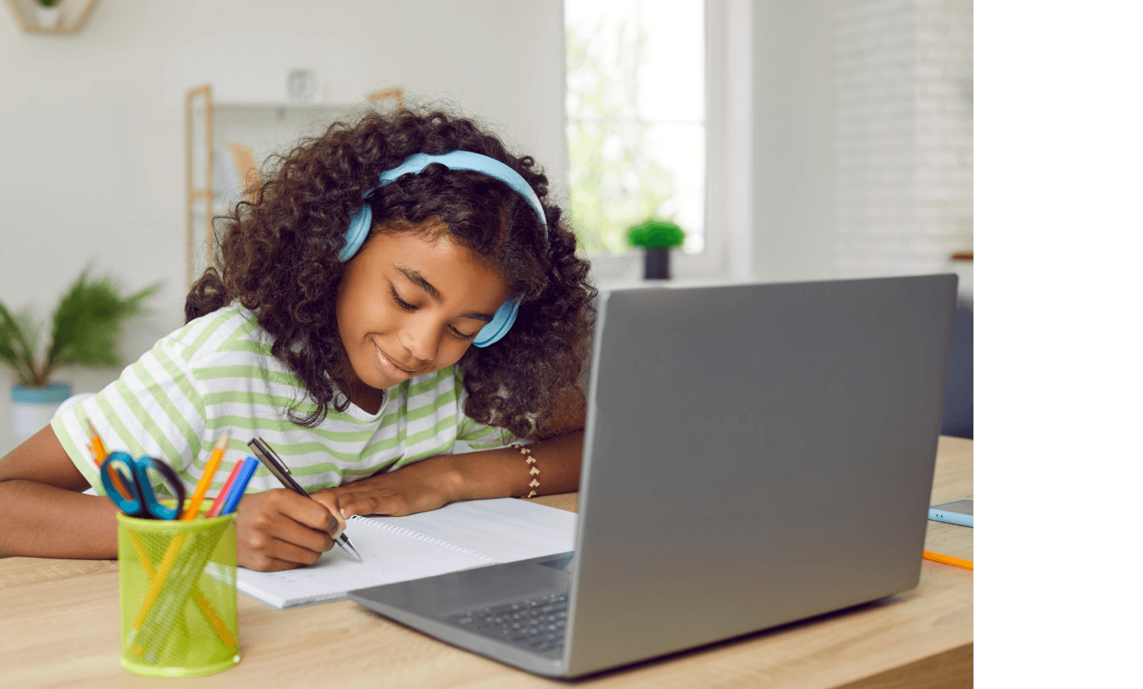 A focused student happily engaged in a learning session with her laptop and notebook.