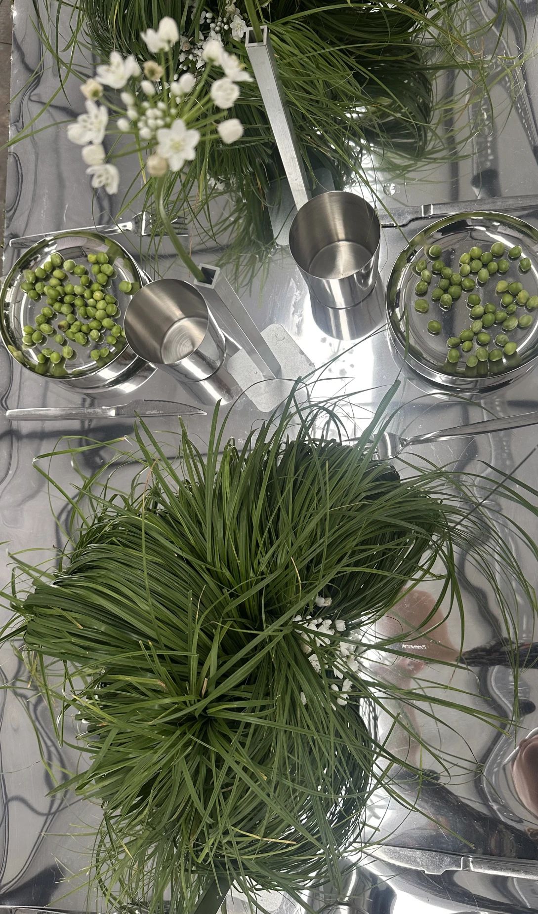 Flores blancas y guisantes sobre una instalación de metal espejado.