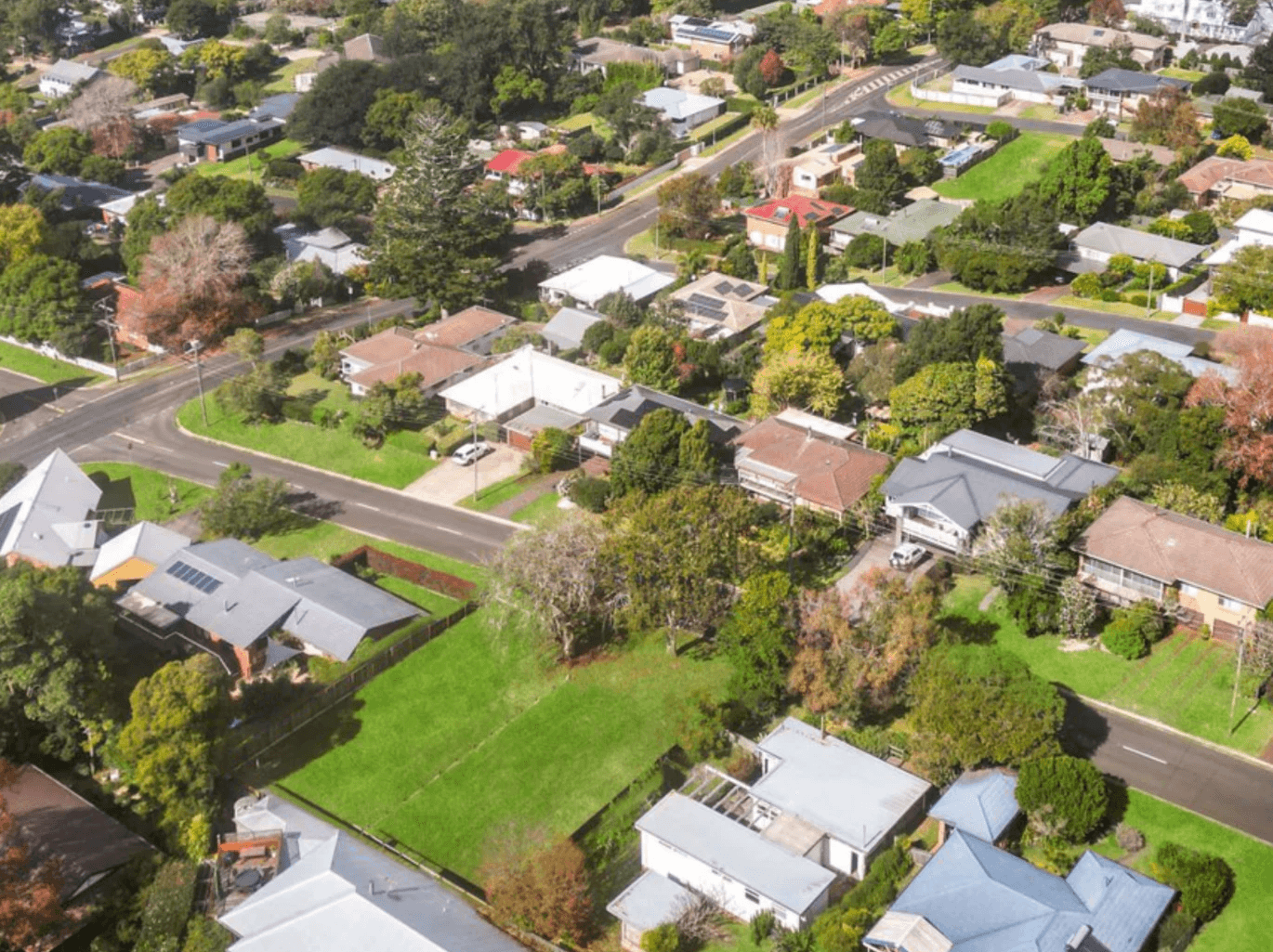 Aerial view of houses and trees with mountains in distance.