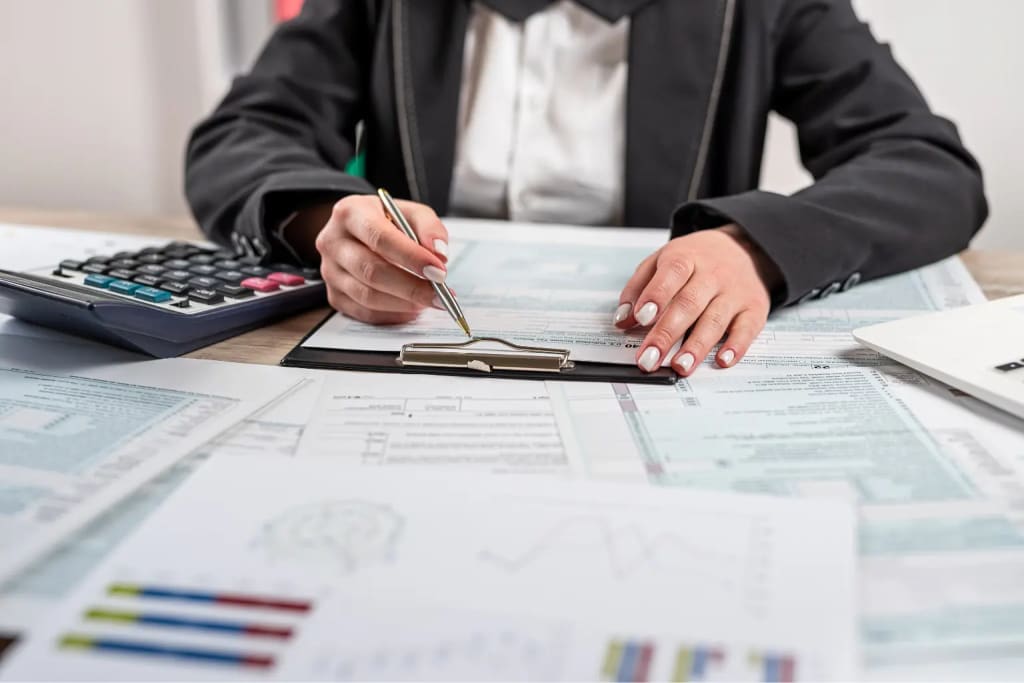 Real estate tax deductions being calculated by a professional filling out IRS tax forms on a clipboard surrounded by financial documents and a calculator