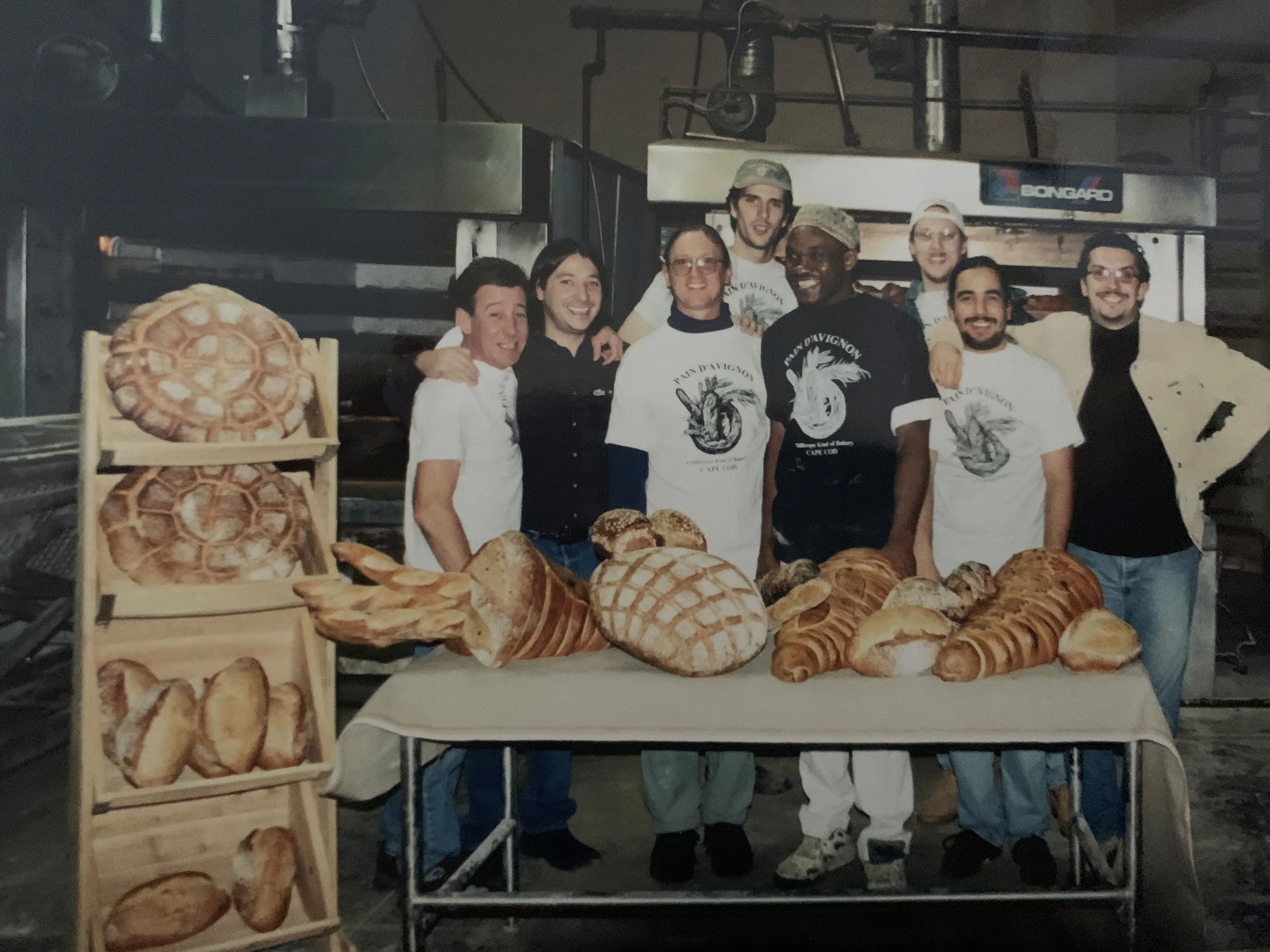 Pain d'Avignon founding team in the bakery surrounded by fresh artisan breads