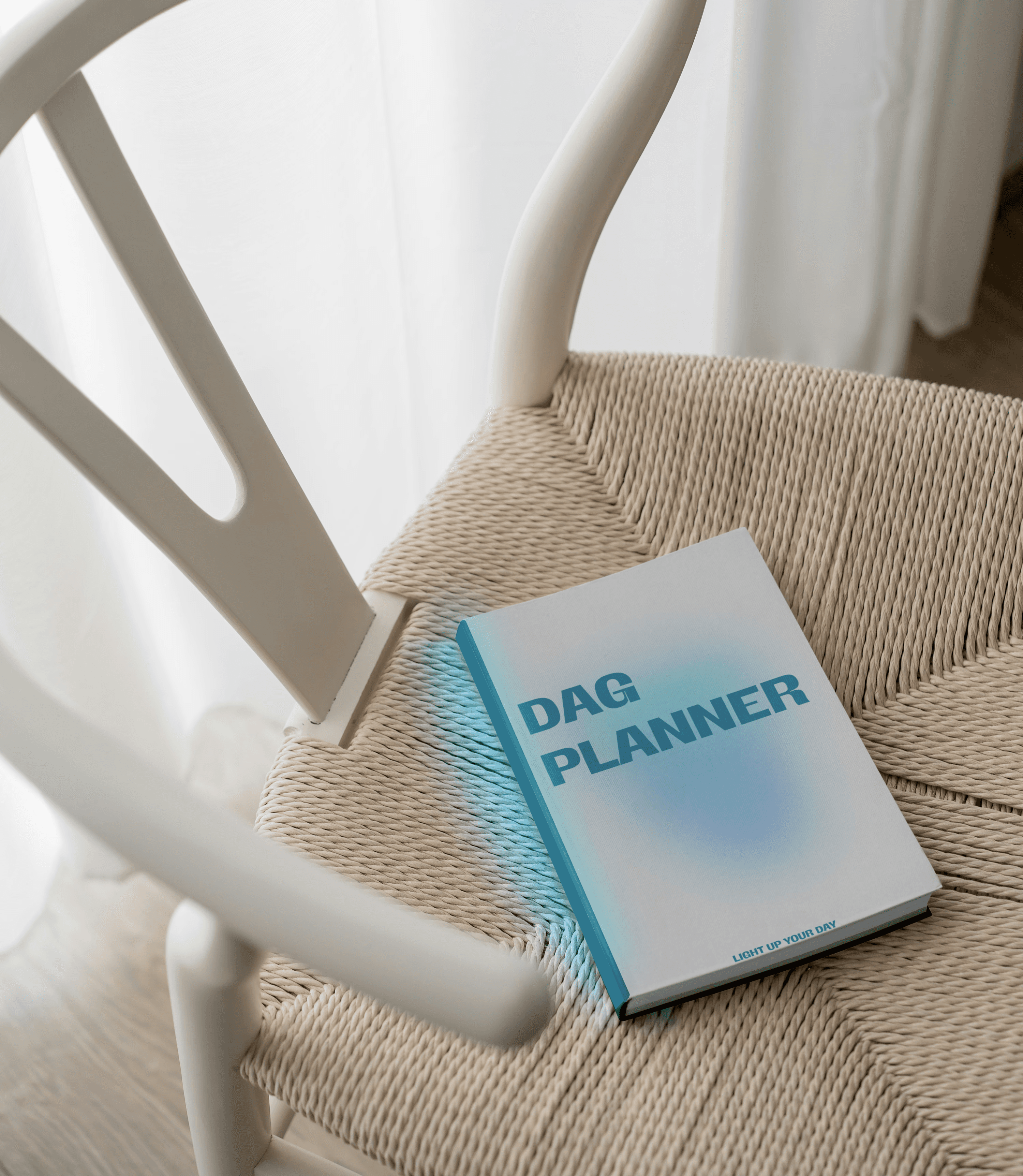 Person wearing black clothing carrying a black tote bag with a green globe-like geometric symbol, standing against a concrete wall in sunlight and shadow.