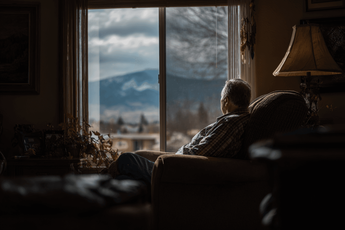 a senior in their home, sitting in their armchair and looking out of the window in Nevada
