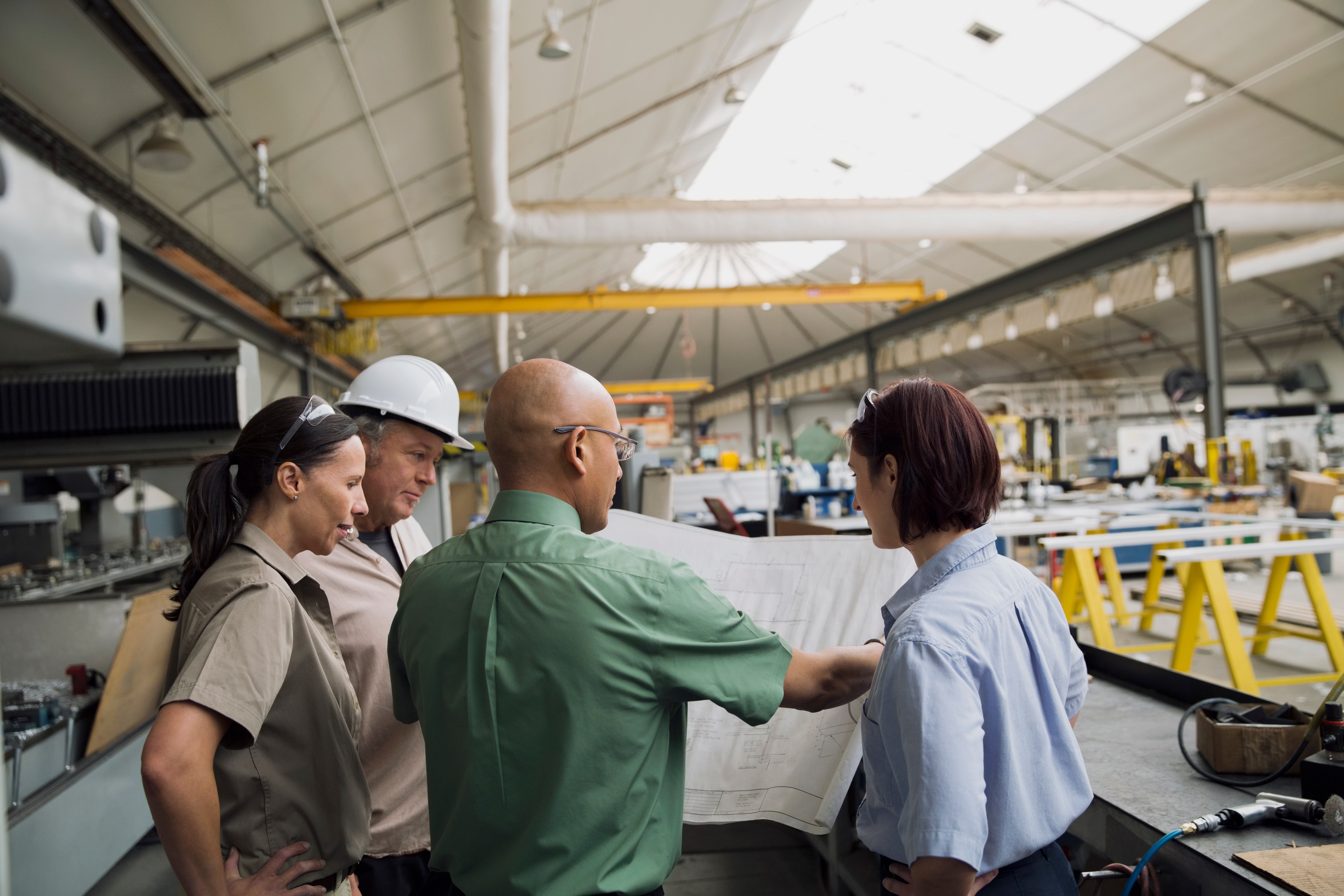 Manufacturing team reviewing operations inside a modern factory, representing manufacturing marketing, digital marketing for manufacturers, and industrial growth strategy.