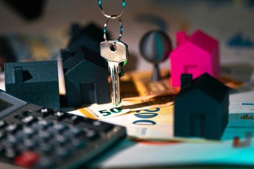 A calculator, keychain, and house model on a table, illustrating the sale of a house