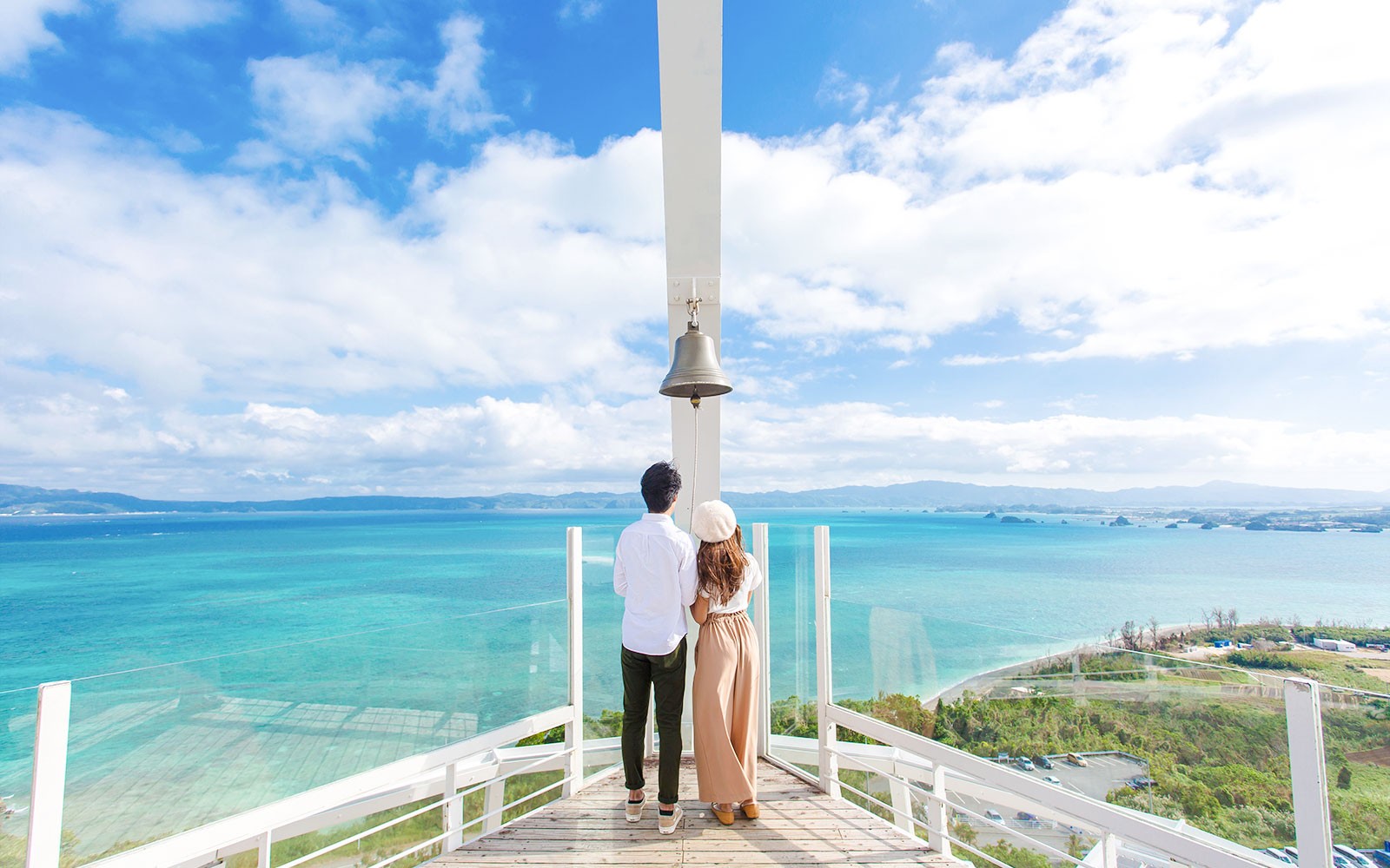 Ζευγάρι στη βεράντα παρατήρησης με καμπάνα που βλέπει πάνω από το γαλαζοπράσινο ωκεανό στο Hakone Kowakien Yunessun, Ιαπωνία.