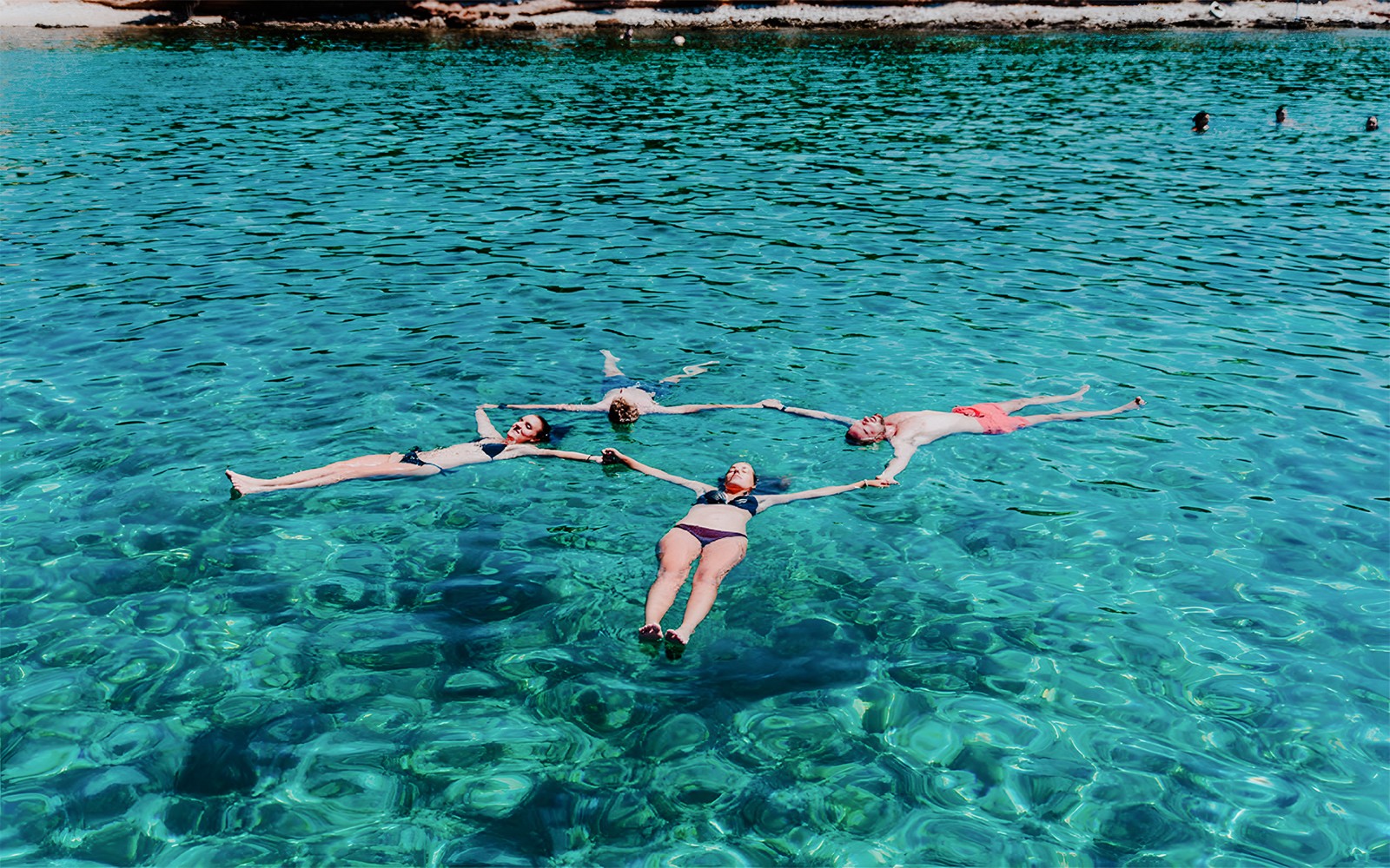 Group swimming in clear waters on Blue Cave, Blue Lagoon & 5 Islands tour.