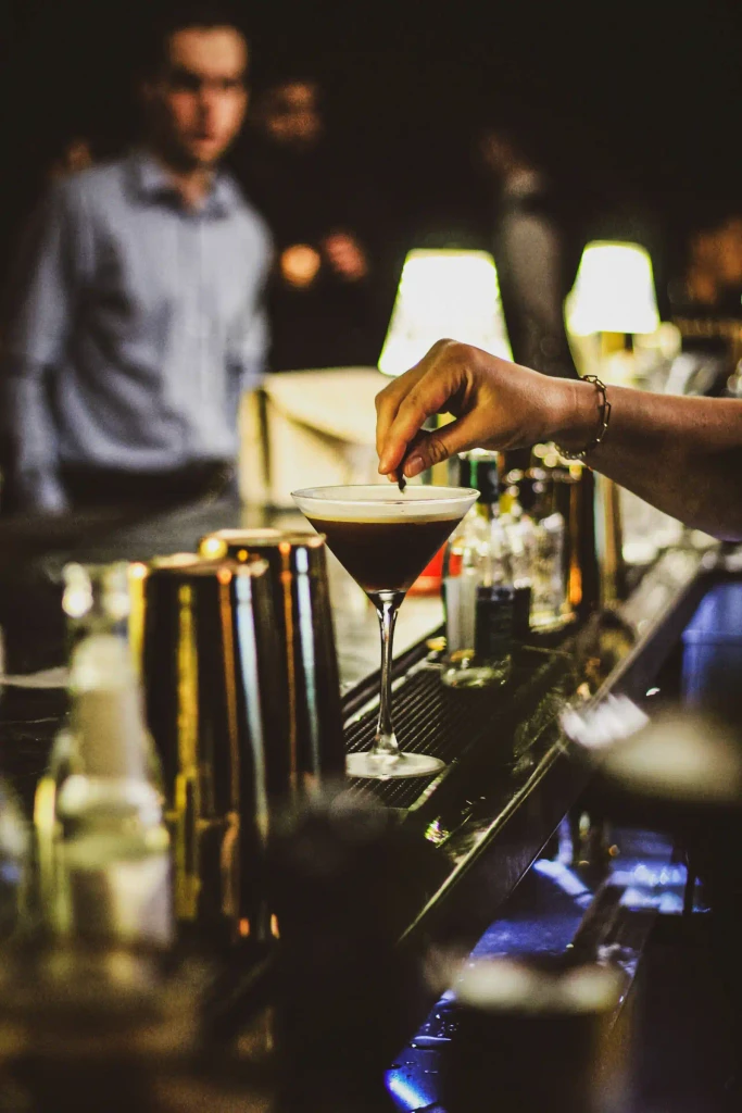 Bartender adding garnish to an espresso martini cocktail.