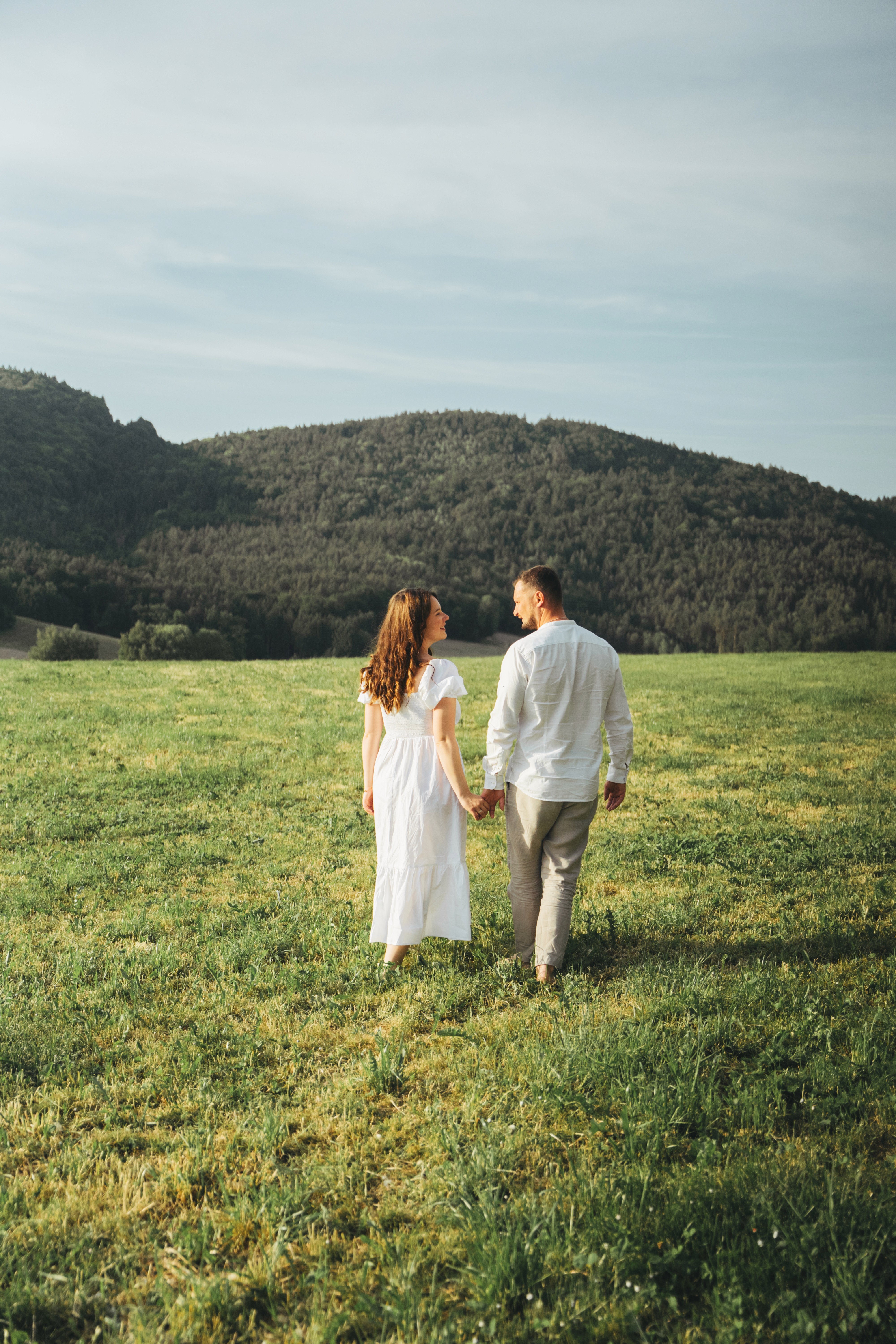 Paar- und Schwangerschaftsfotografie in Bogen, Niederbayern – werdende Eltern spazieren über eine Wiese.