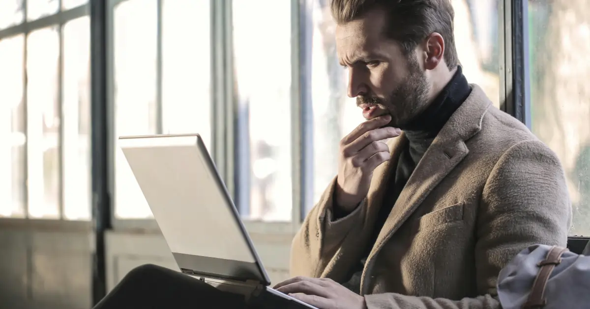 Man thoughtfully looking at his laptop, symbolizing website redesign decisions. 