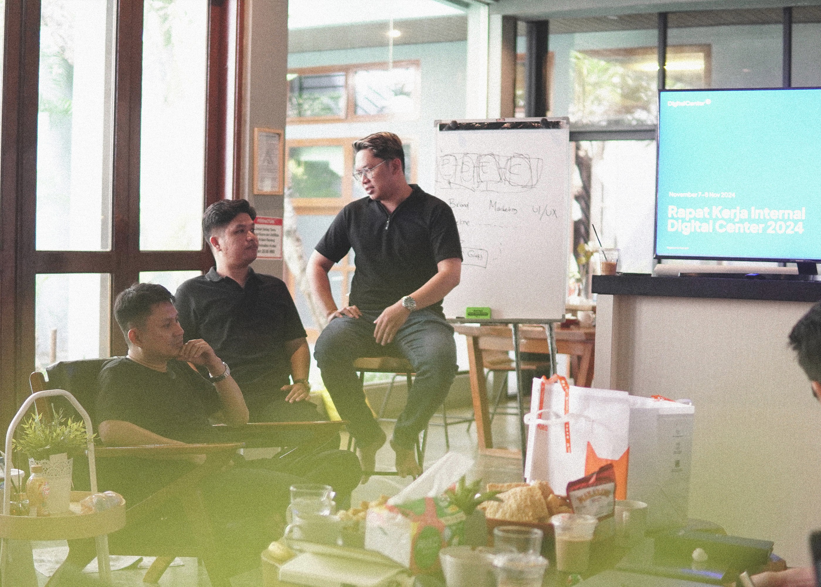 Four diverse professionals collaboratively working on a laptop, with one person pointing at the screen while others observe.