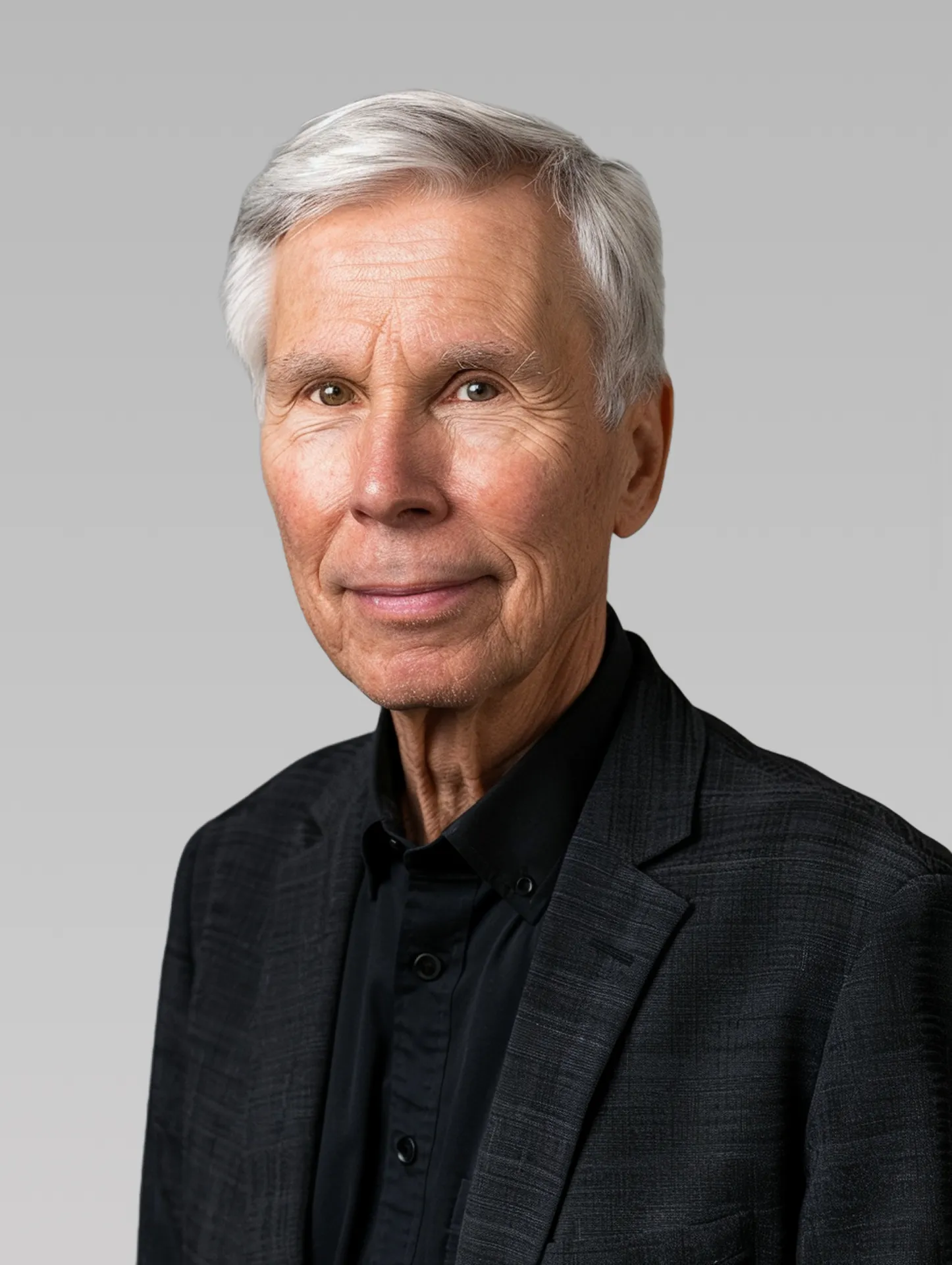 Close-up portrait of a old man in a black suit, set against a light background
