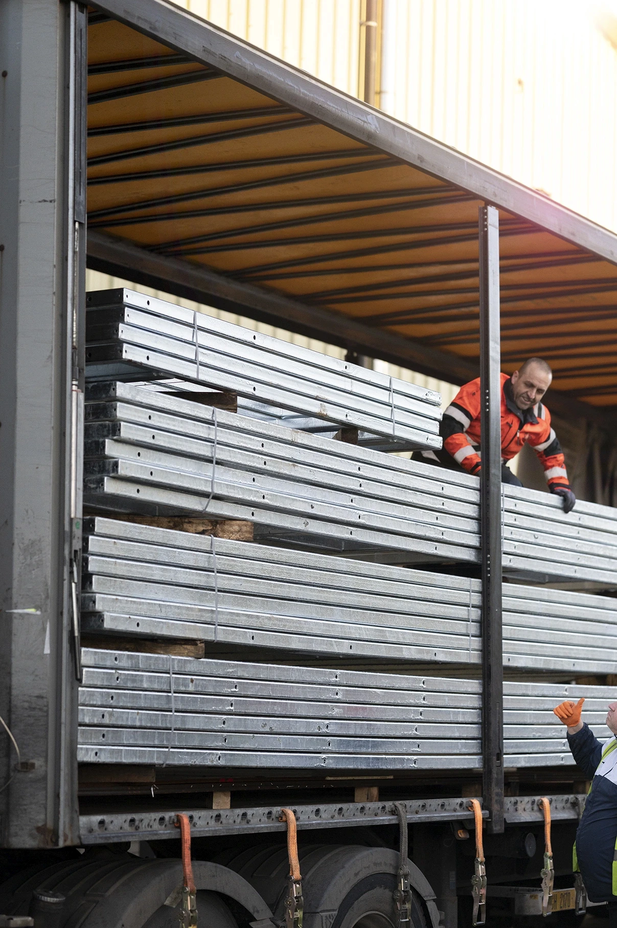 CASC employee operating a forklift to unload stacked steel sections from a lorry at an industrial site.