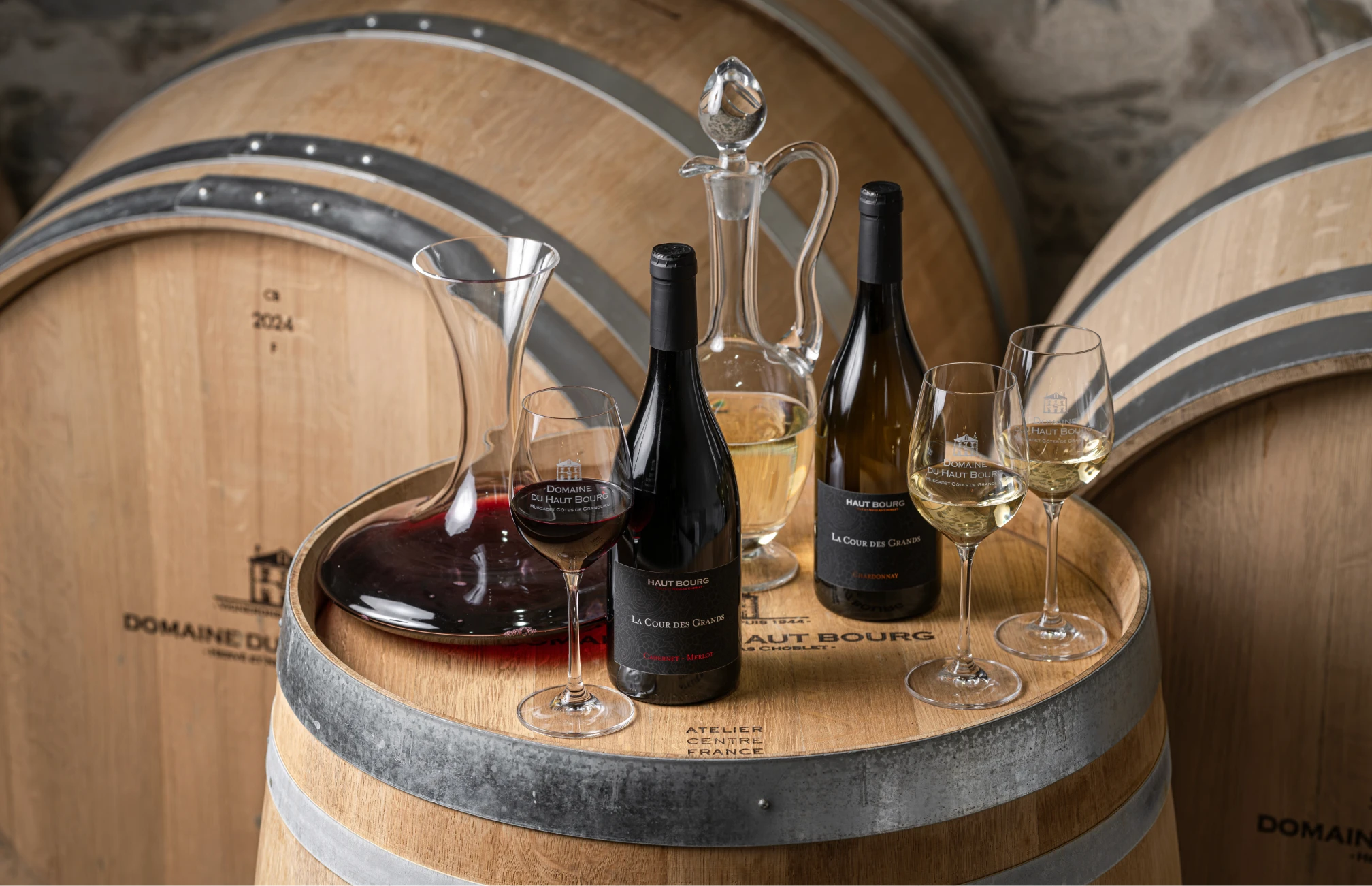 Bottles, carafe and wine glasses on an oak barrel