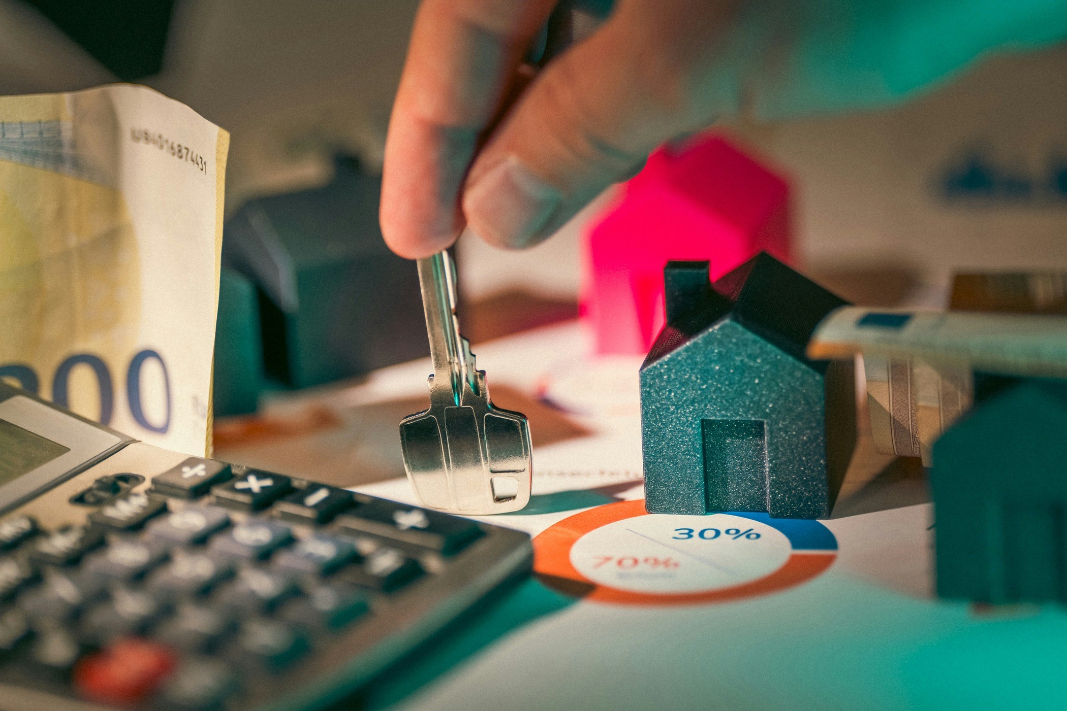 A model house on a desk with a key, calculator, bill