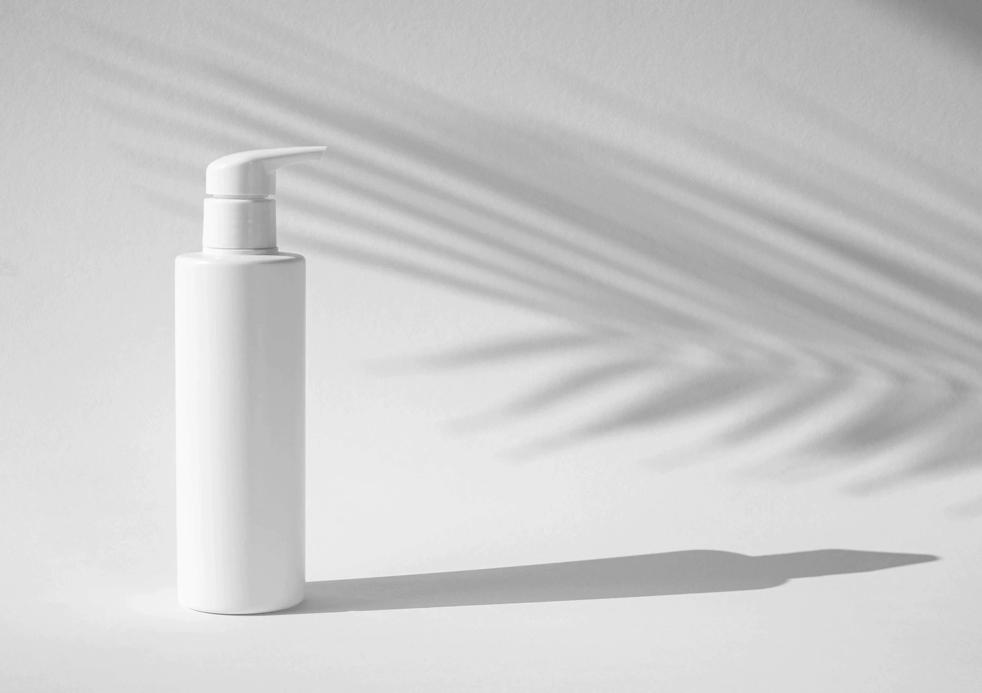 white skincare bottle with pump and shadow