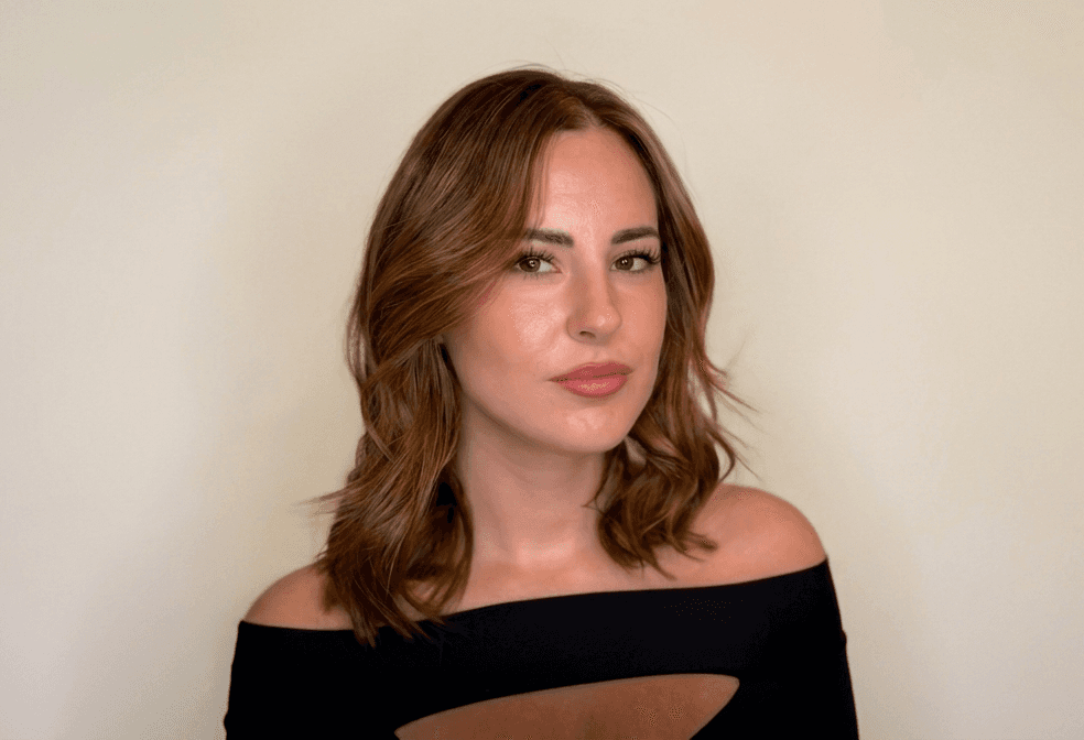 A luxurious indoor pool area with a panoramic view of a city at sunset. Comfortable lounge beds with soft fabrics surround the pool, while warm ambient lighting enhances the sophisticated atmosphere. The space combines modern elegance with a tranquil vibe.