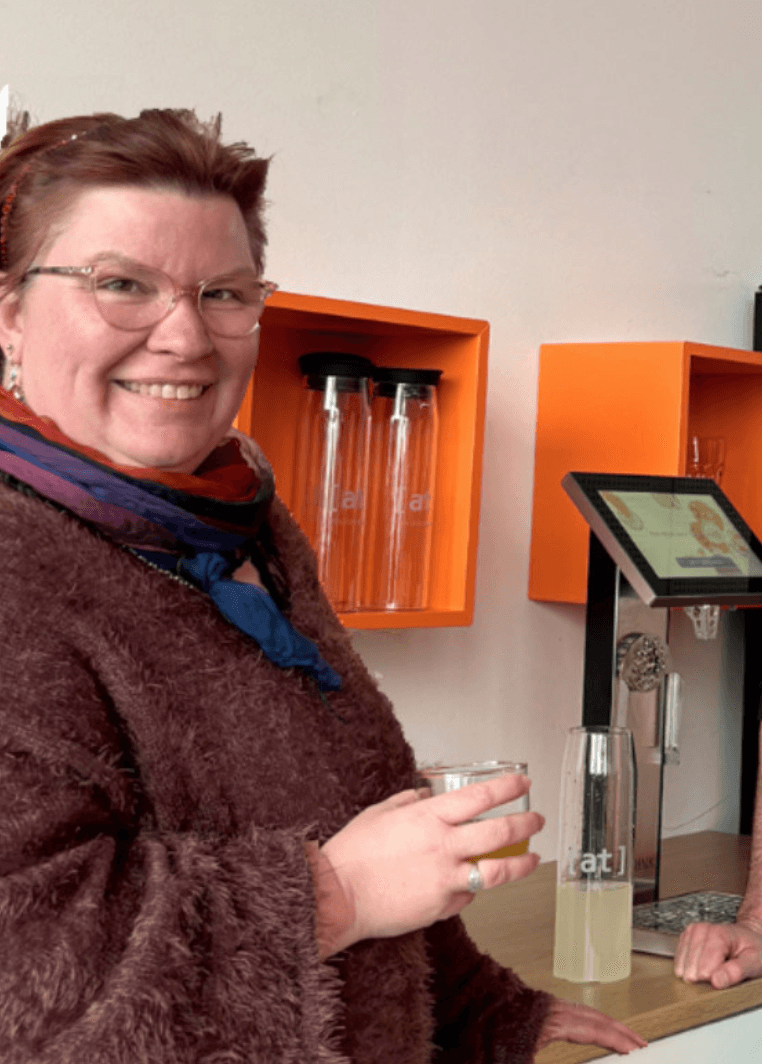 Office Managerin Dawina lächelnd mit einem frischen Getränk in der Hand