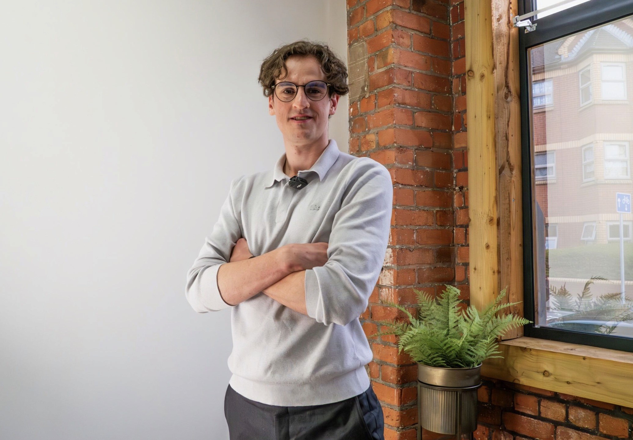 A person with glasses and a sweater standing near an open door.