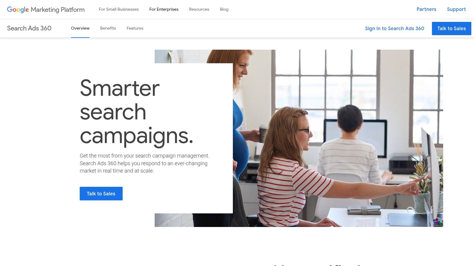 A marketing team collaborating around a table, analyzing charts and graphs on a laptop, representing the enterprise-level analysis enabled by SA360.