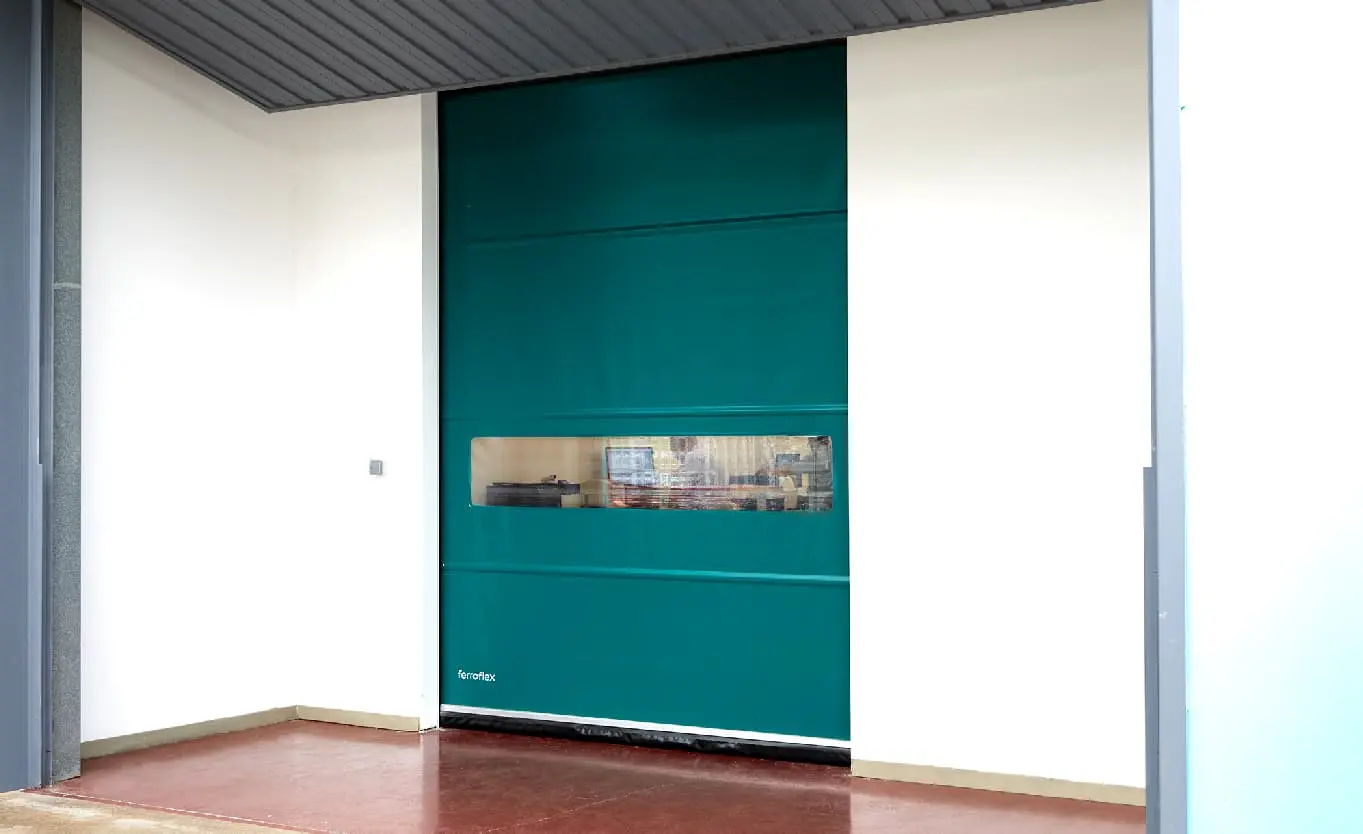 Puerta metálica de apertura rápida en color celeste agua, con aislamiento térmico y sistema antirrobo. Perfecta para espacios limpios y logística de alto rendimiento.