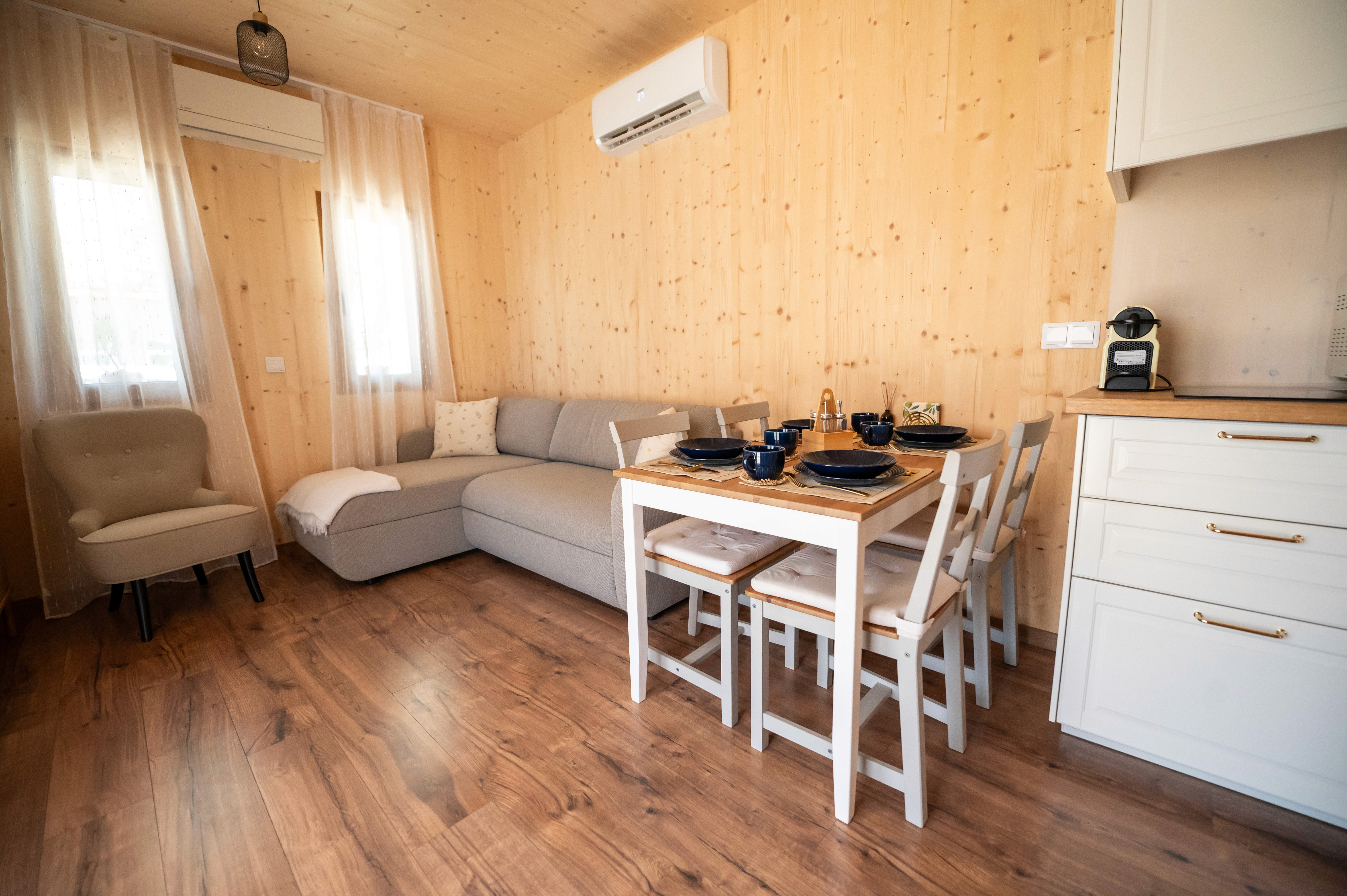 Nappali fotója szürke sarokkanapéval és fehér vidéki hangulatú étkező szettel.