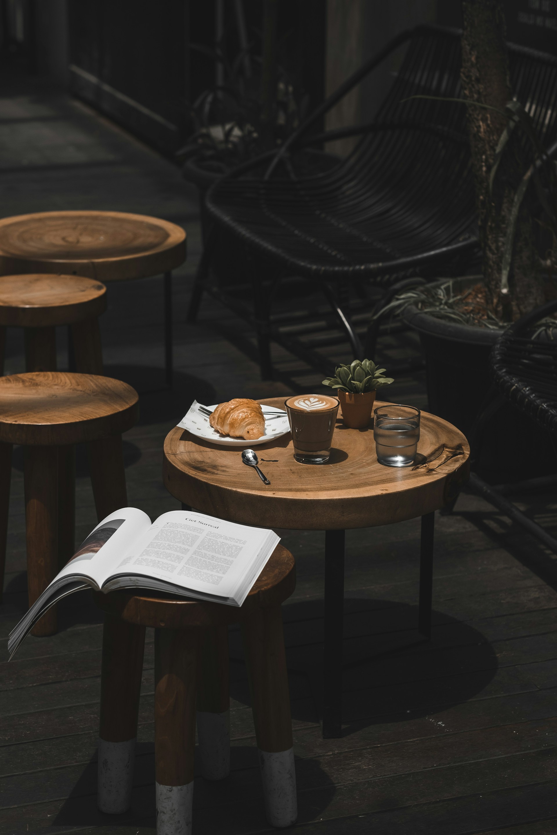 A table with an open book beside a steaming cup of coffee.
