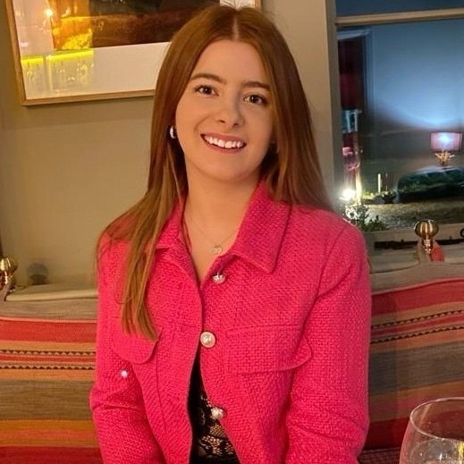 A young professional woman with long hair wearing a pink coat