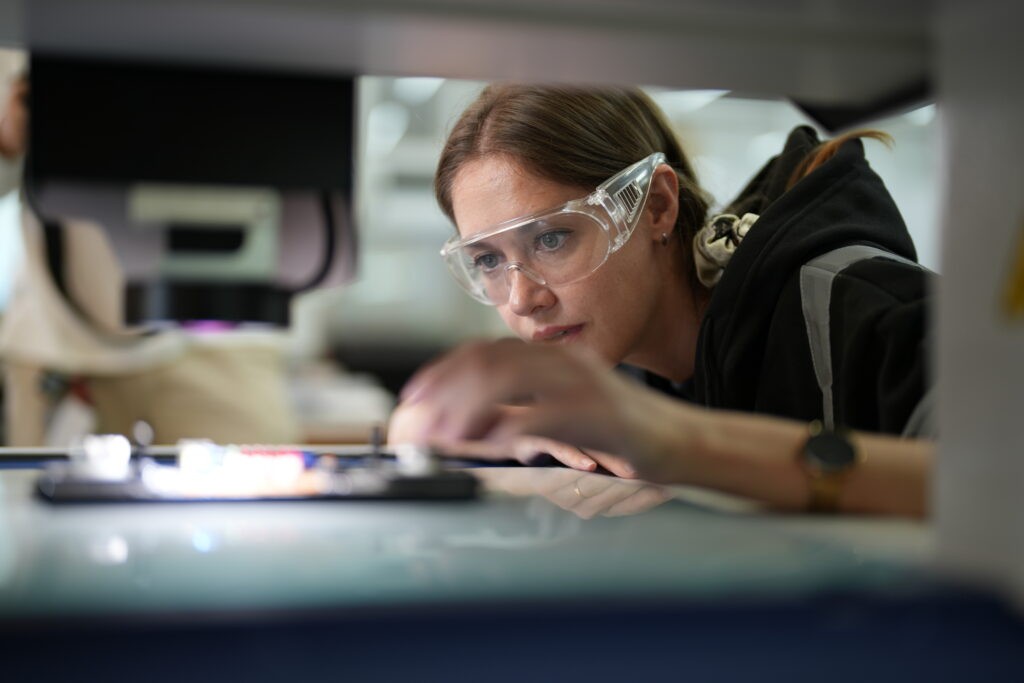 Photo of a woman in safety goggles working in industrial automation