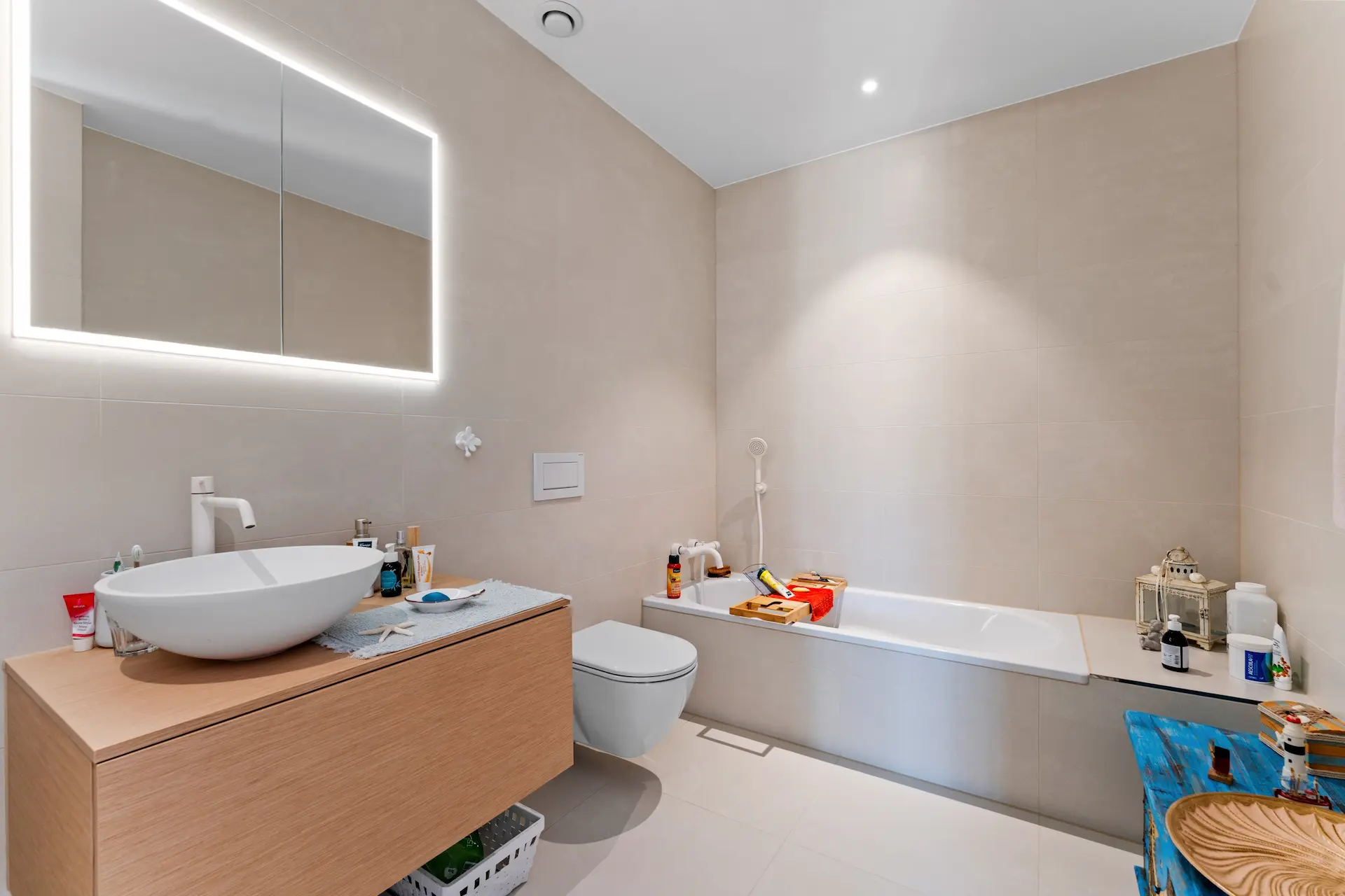 Helles und beiges Badezimmer mit Deckenspot über Badewanne