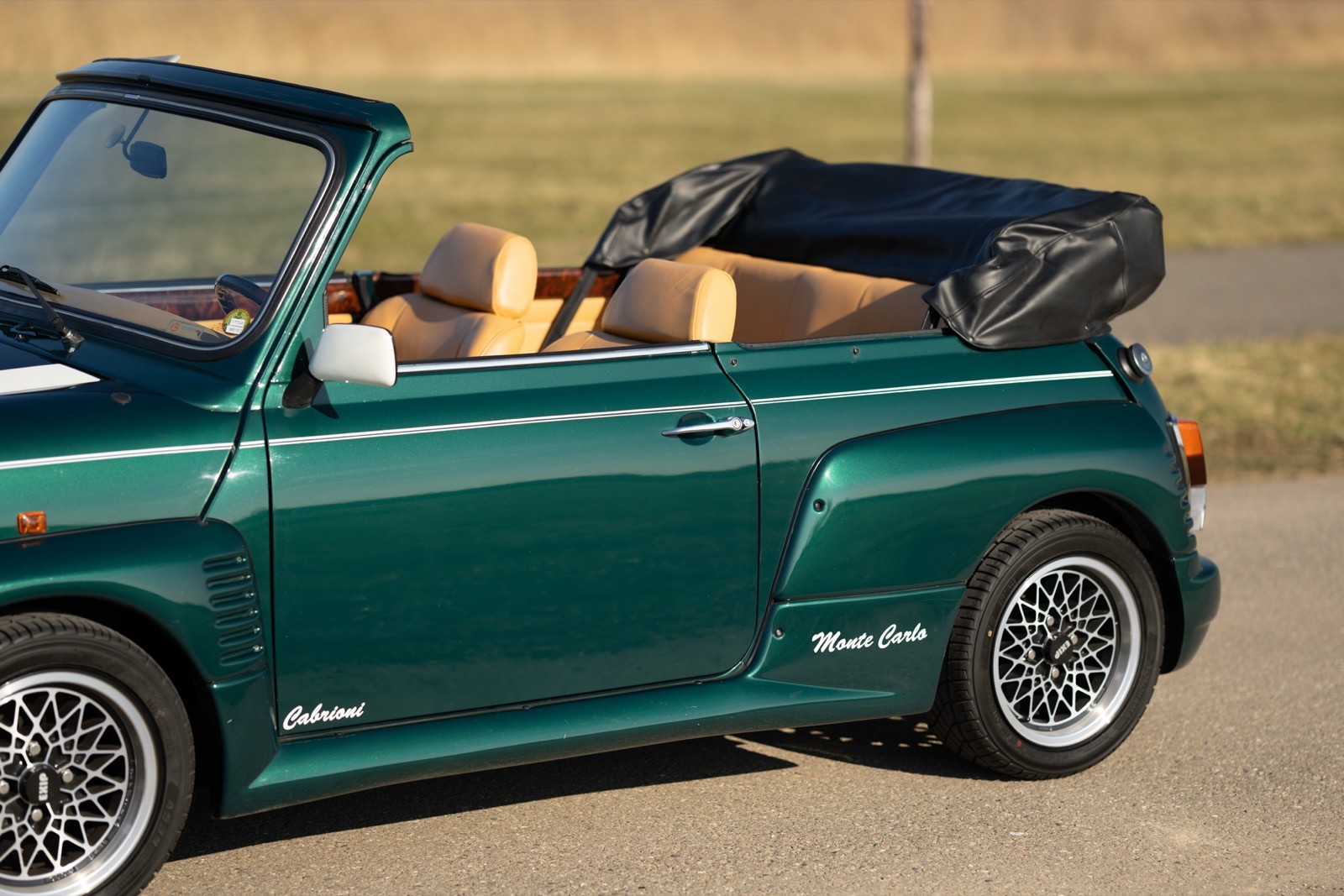 A green convertible car parked with the top down, showcasing its sporty design and stylish wheels.