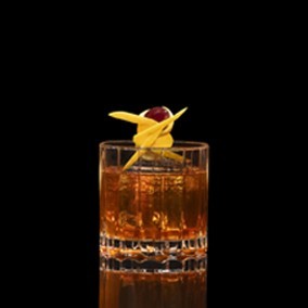 A closeup of a Prohibition Old Fashioned drink against a dark background.