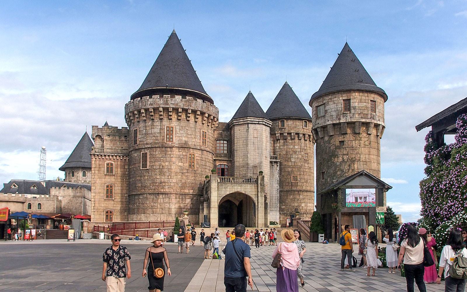 Stone castle towers at Ba Na Hills with tourists exploring the courtyard.