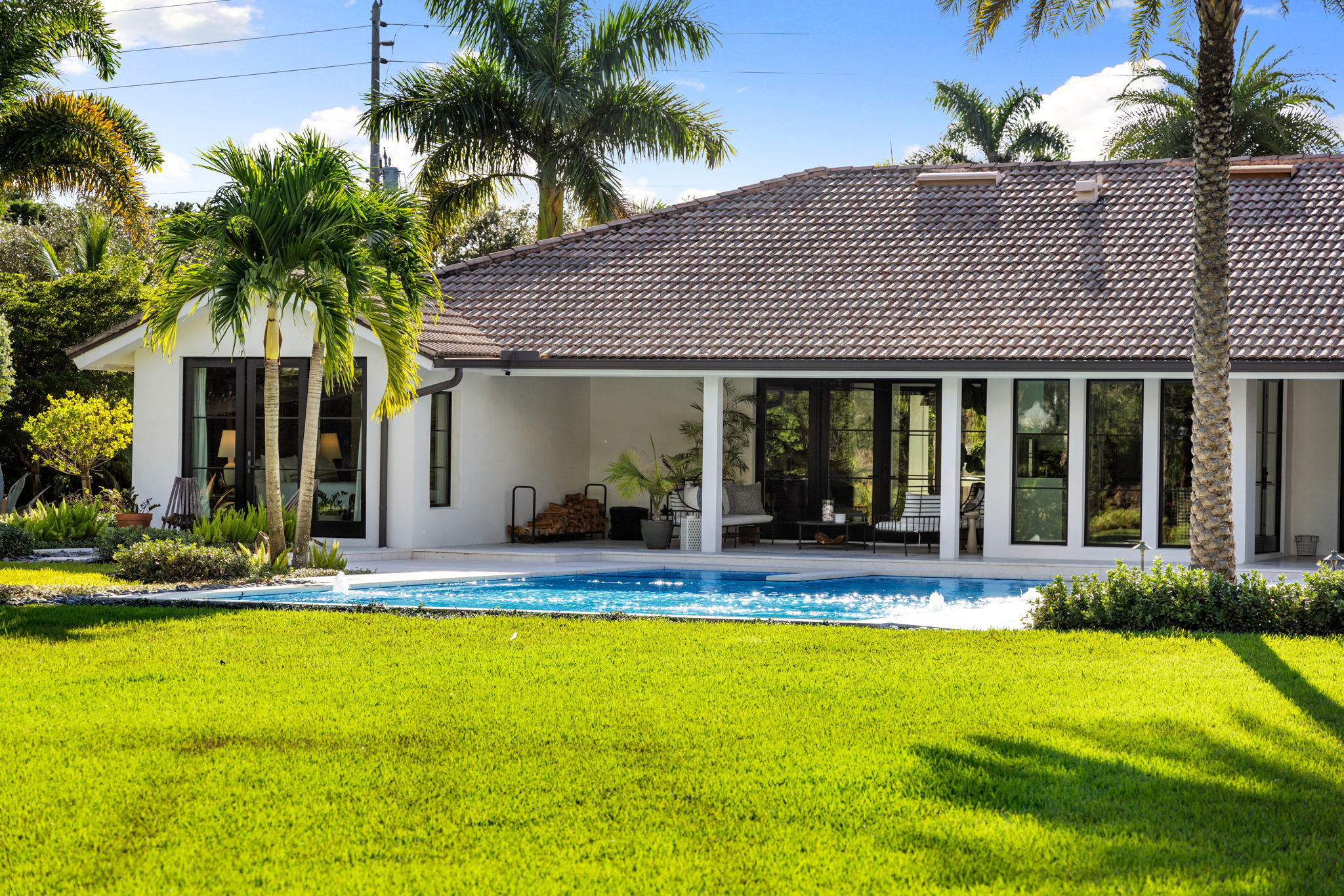 a large white home with a pool and large field in the foreground