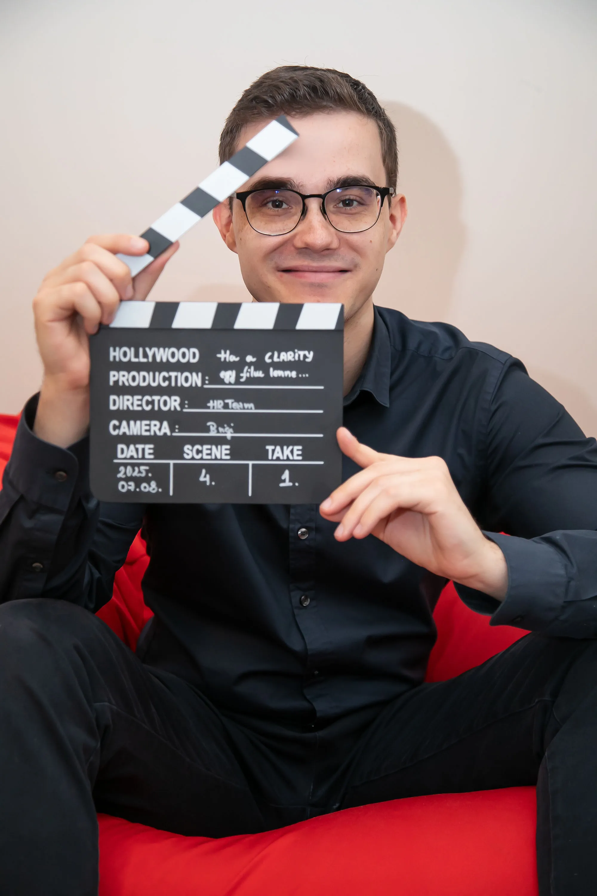 Kolléga filmes klapperboardot tart a keze előtt, játékosan utalva egy céges videóforgatásra
