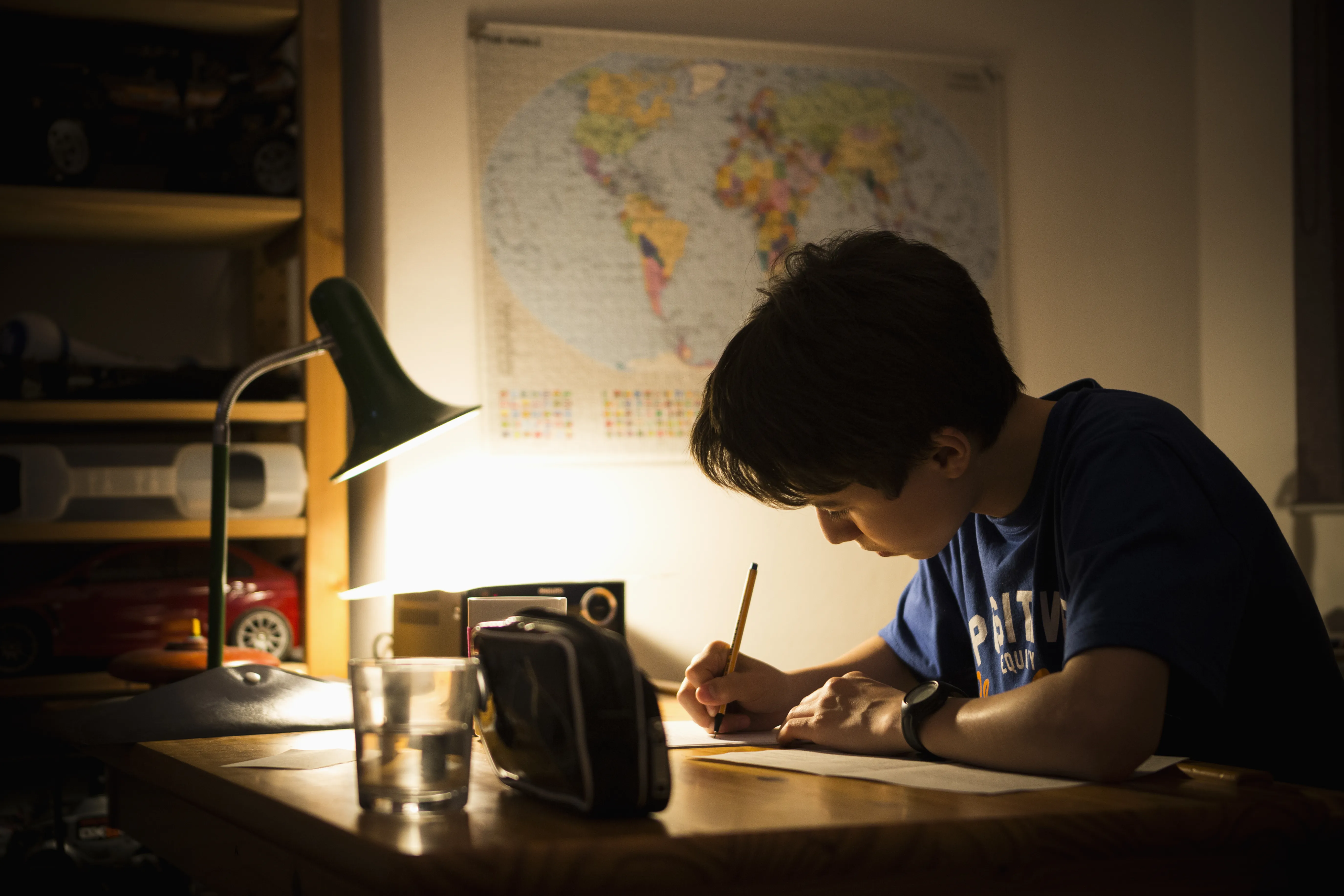 Little boy writing under dim lamp light